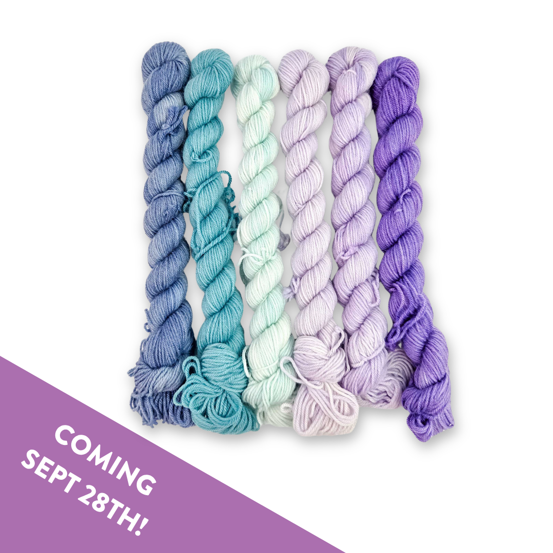 Six mini skeins of Molly Klein Design Mermaid Lagoon sock yarn in blue, teal, mint, lilac and purple, with a Coming Sept 28th banner