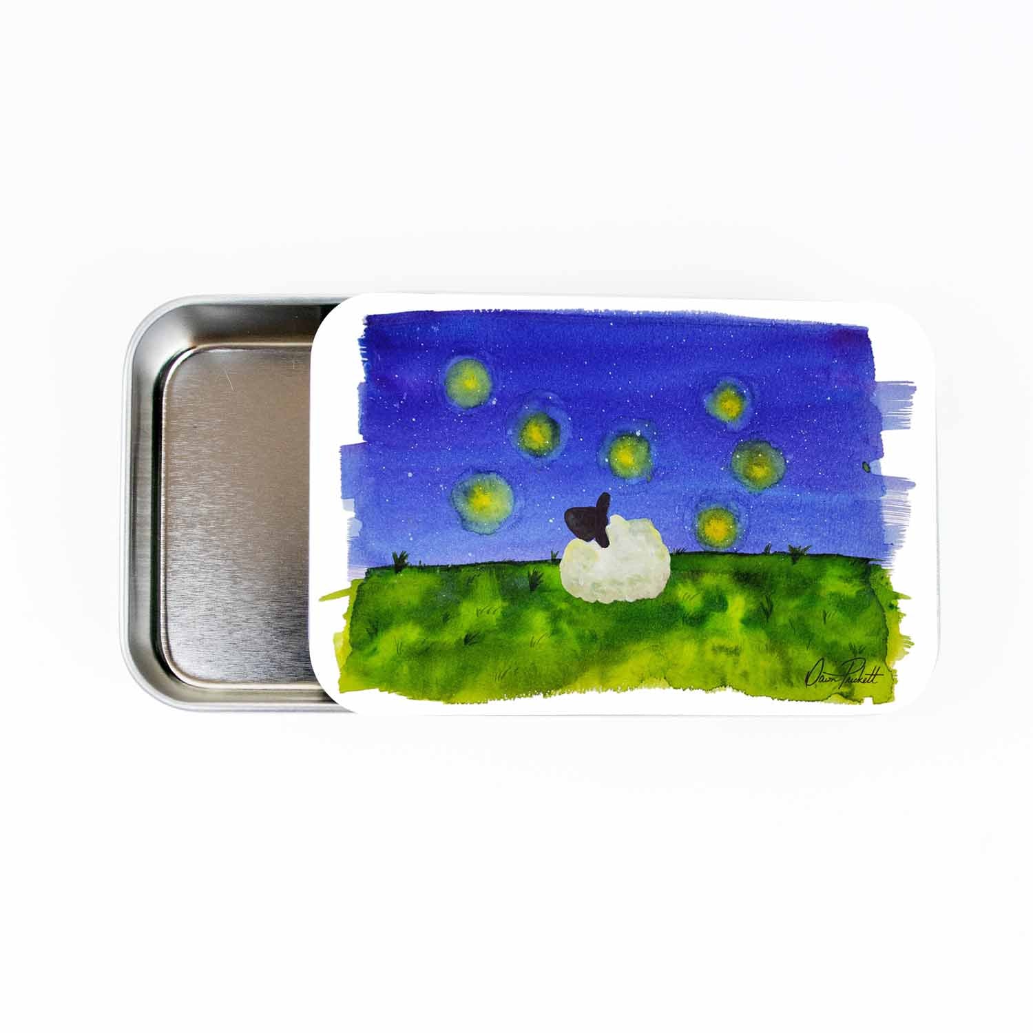 Large slide-style silver storage tin with watercolor scene of a white sheep sitting on a green hillside watching glowing fireflies against a deep blue starry night sky, signed by Dawn Prickett