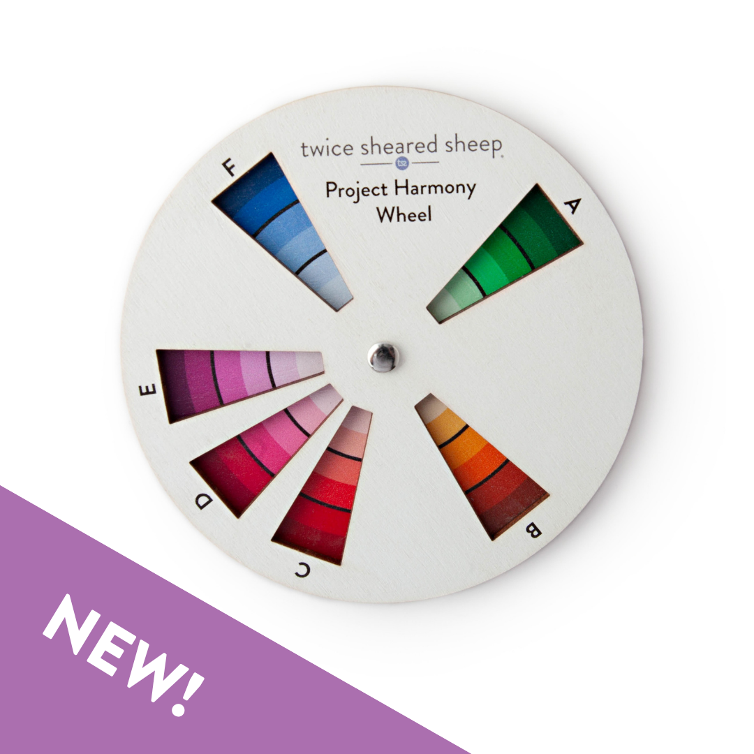 Round white wooden Project Harmony Color Wheel with six labeled windows showing green, orange, red, pink, magenta and blue shade gradients, with a purple NEW banner