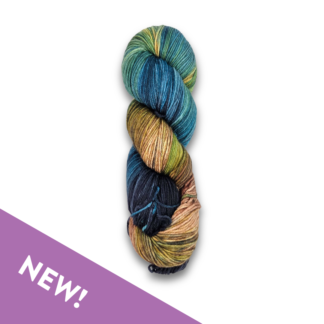 Skein of Yarnaceous Fibers Smuggler's Bay fingering weight sock yarn in deep navy, teal, gold and copper, with a purple NEW banner