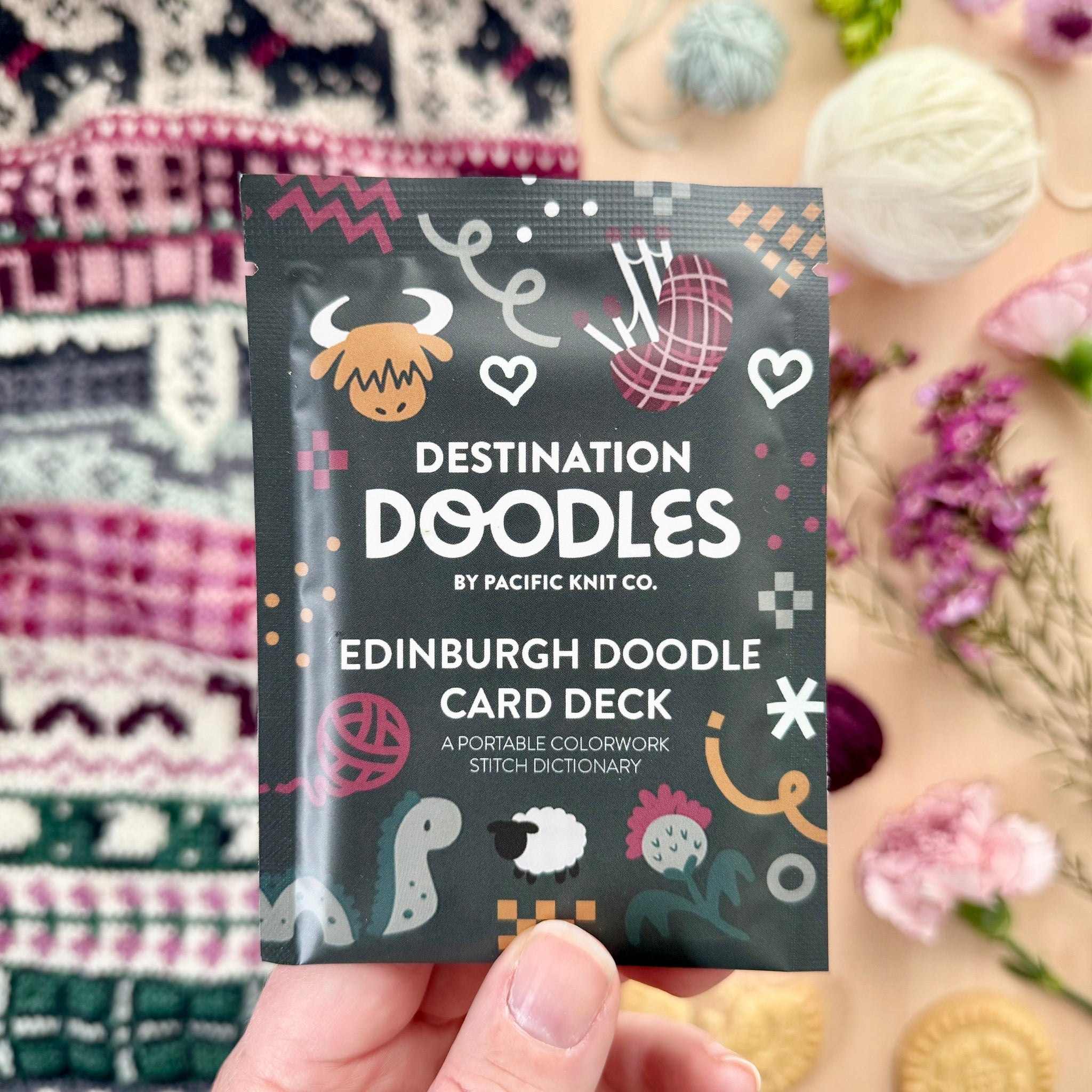 Hand holding the Edinburgh Destination Doodle Card Deck foil pack by Pacific Knit Co