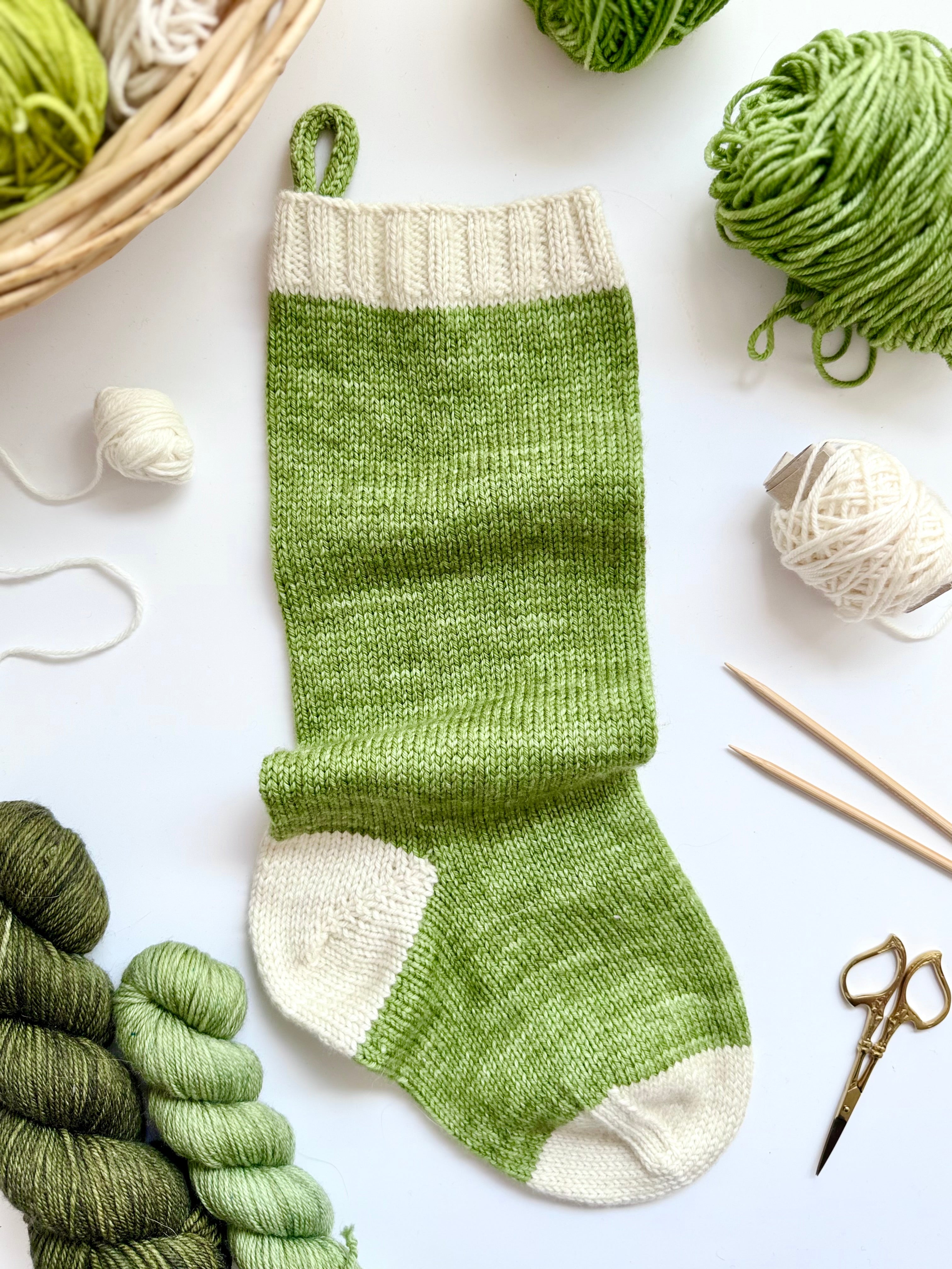 Green and cream Base Doodle Stocking with a hanging loop, yarn and scissors