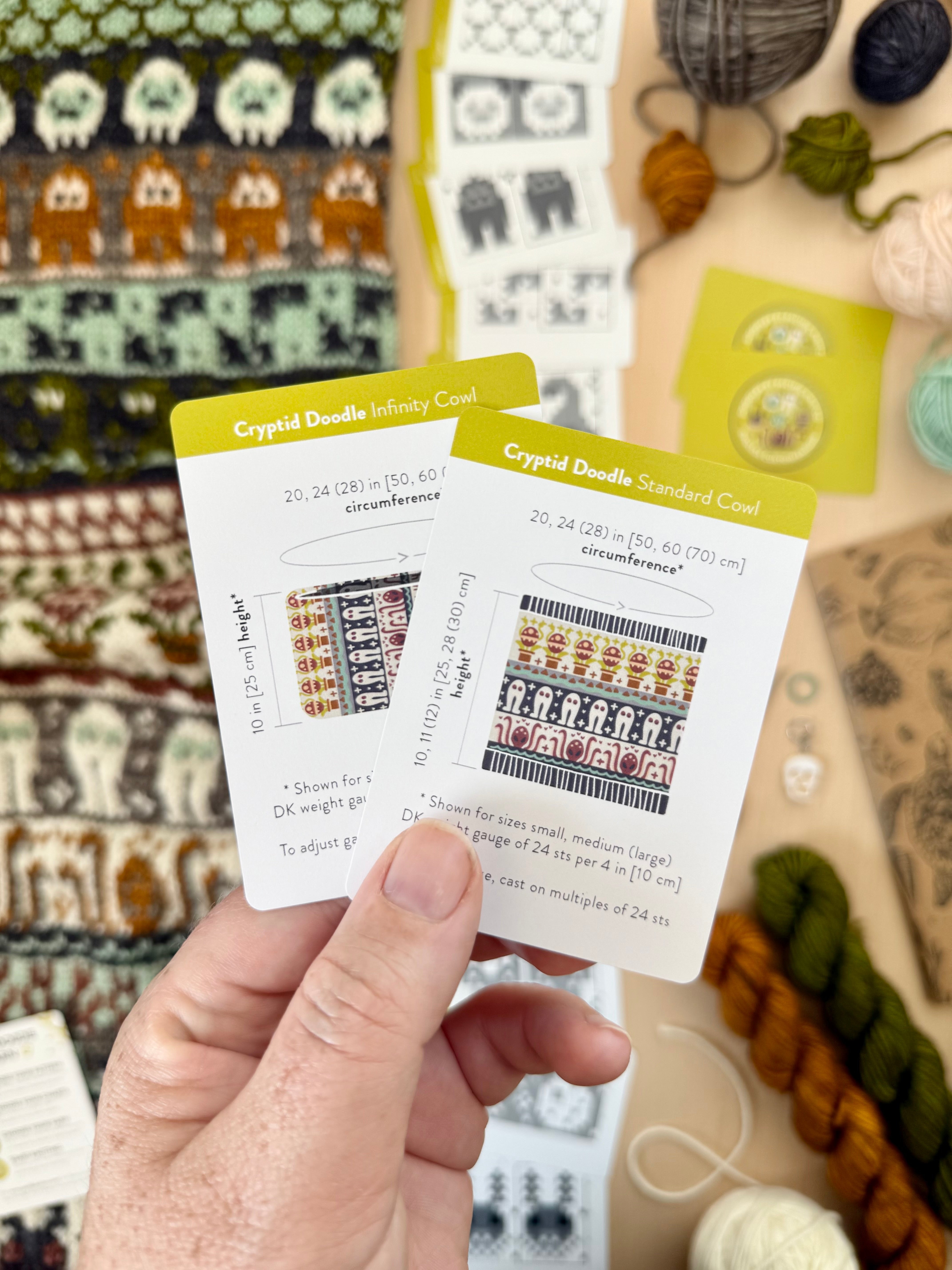 Hand holding the Cryptid Doodle Infinity Cowl and Standard Cowl schematic cards