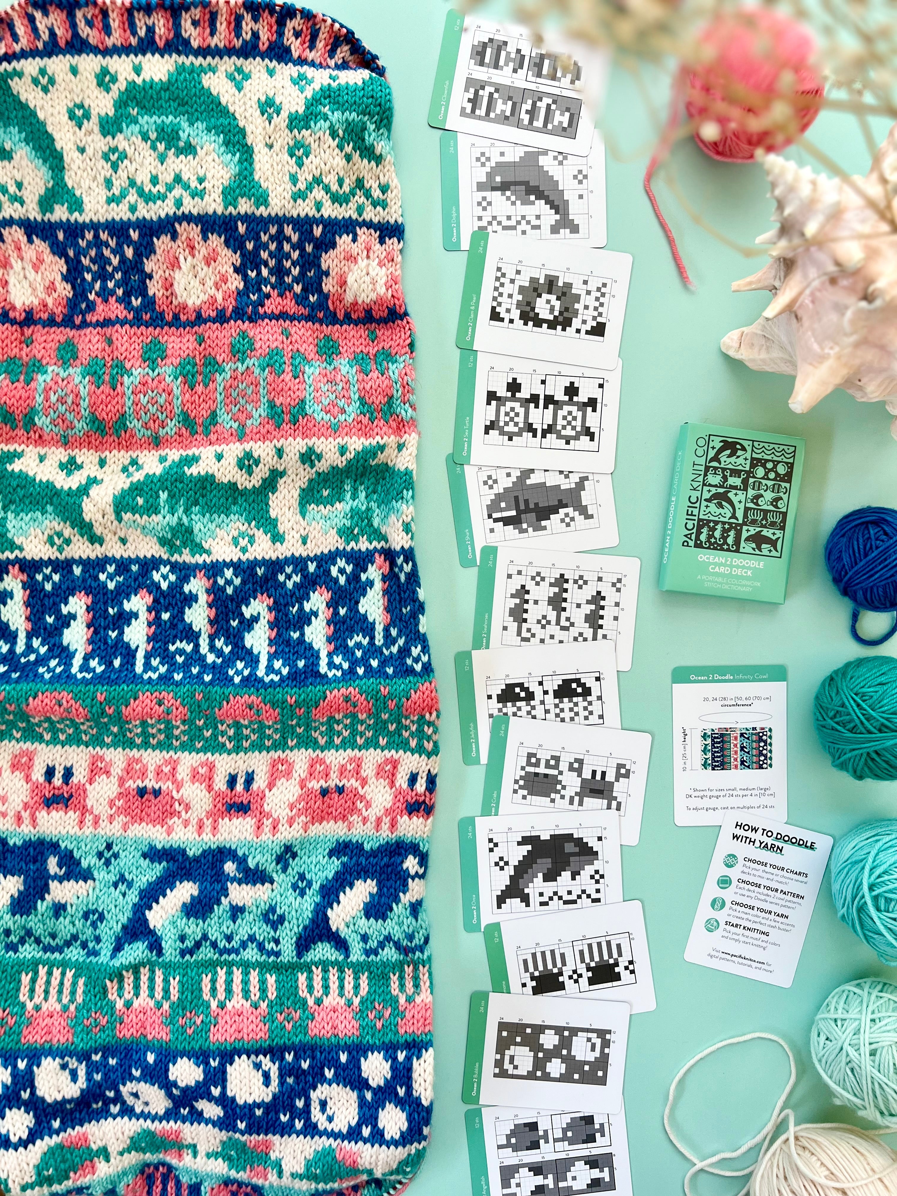 Ocean 2 Doodle colorwork cowl with dolphins and coral beside chart cards