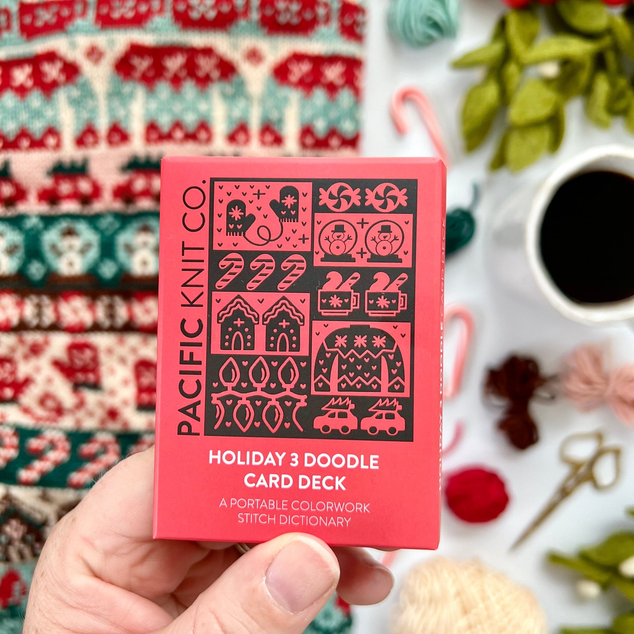 Hand holding the red Holiday 3 Doodle Card Deck by Pacific Knit Co tuckbox