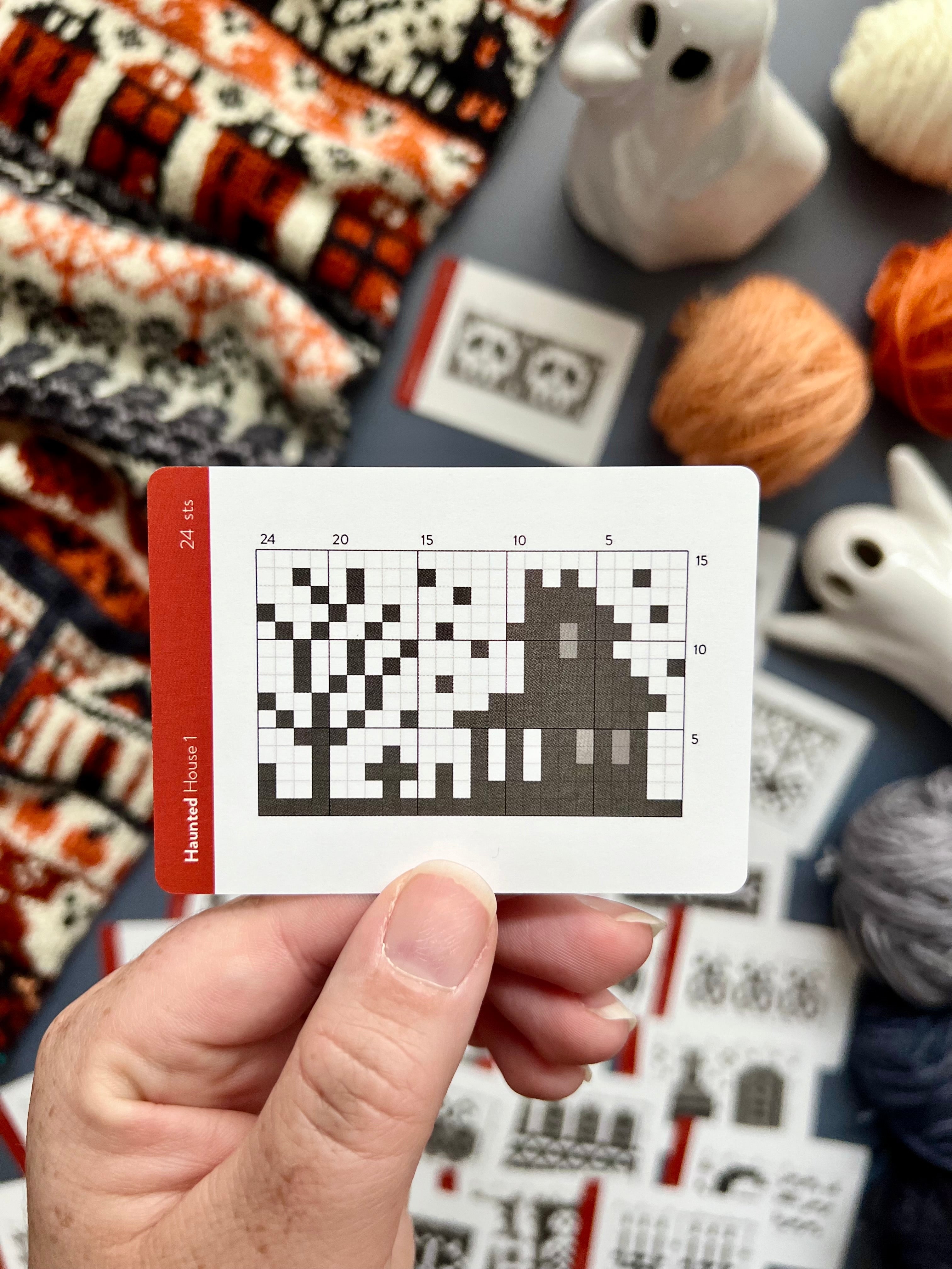 Hand holding a Haunted Doodle haunted house colorwork chart card
