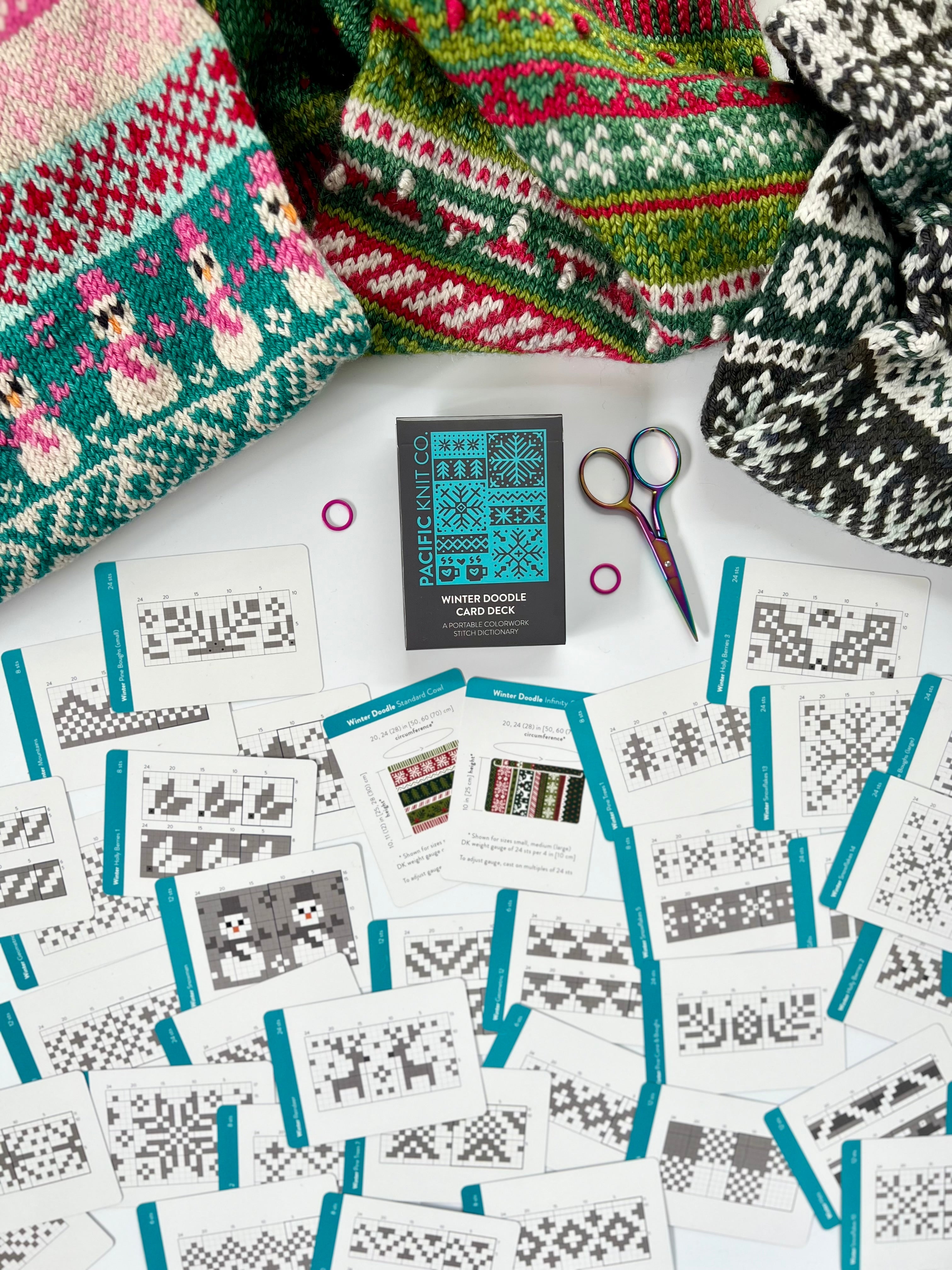 Winter Doodle deck surrounded by scattered chart cards and holiday colorwork knits