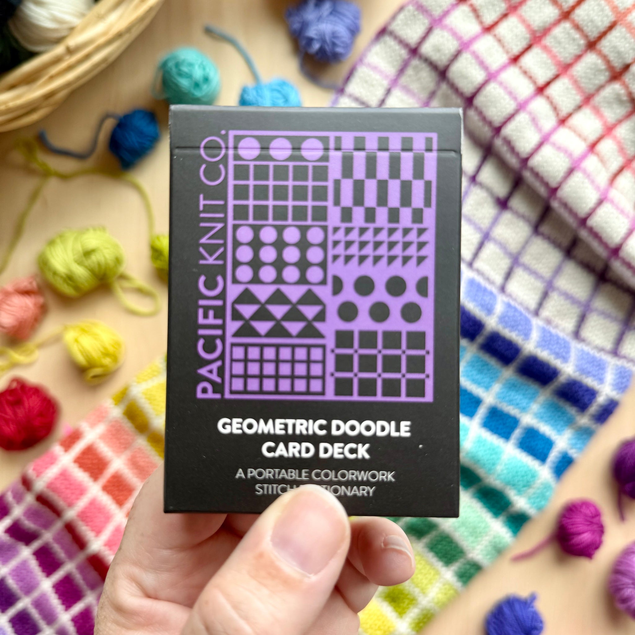 Hand holding the purple and black Geometric Doodle Card Deck by Pacific Knit Co tuckbox