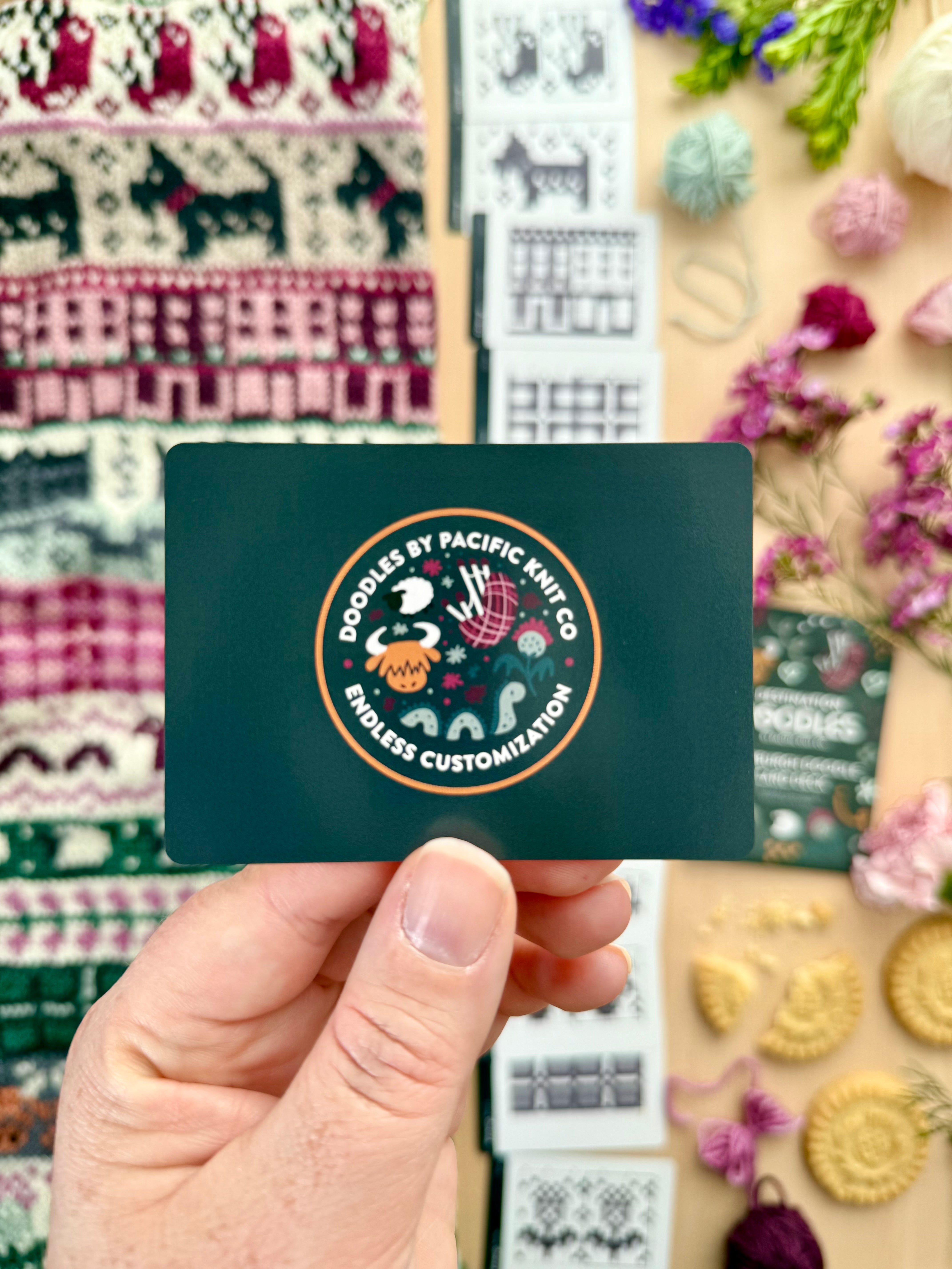 Hand holding the green Pacific Knit Co card back with the Doodles logo