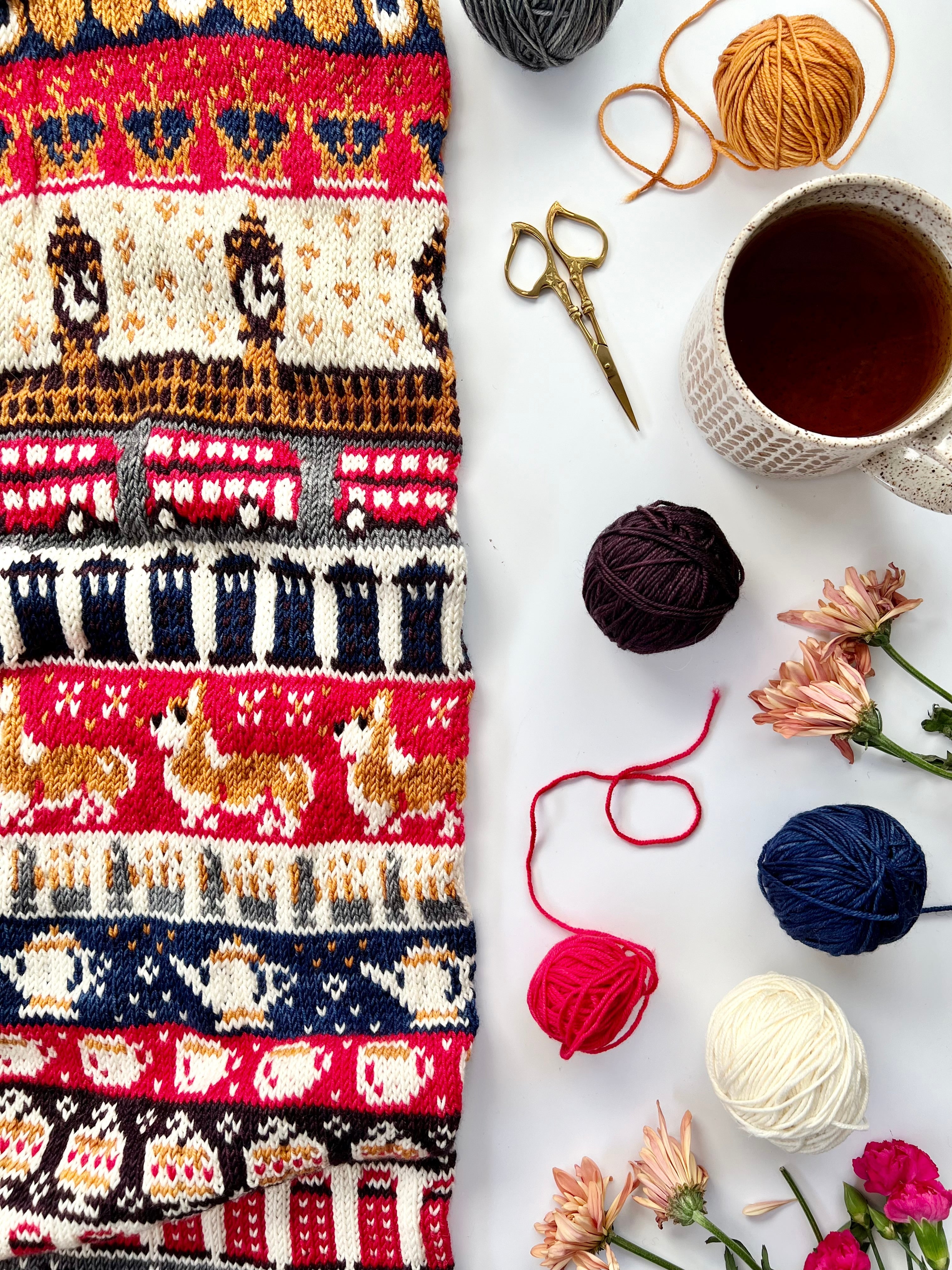 London Doodle colorwork knit with Big Ben and bus motifs beside yarn balls