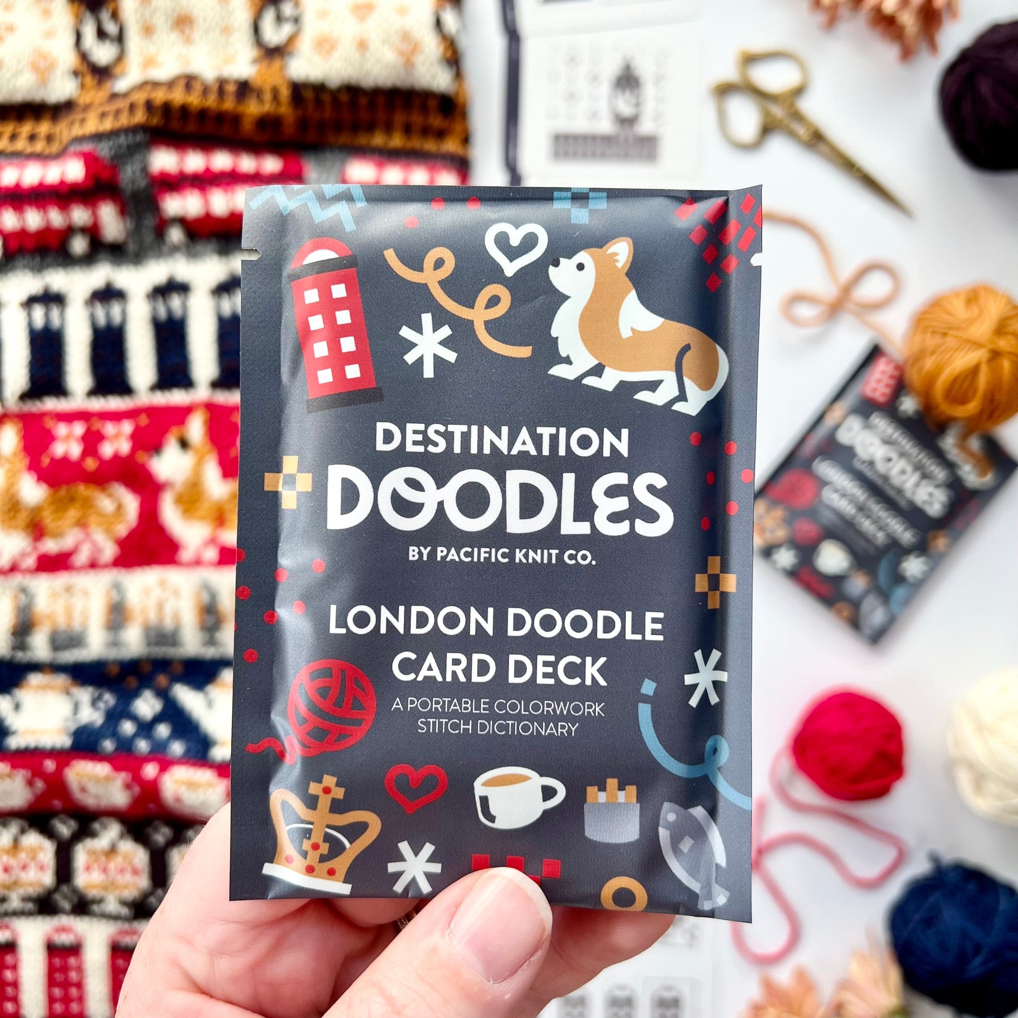 Hand holding the London Destination Doodle Card Deck foil pack by Pacific Knit Co