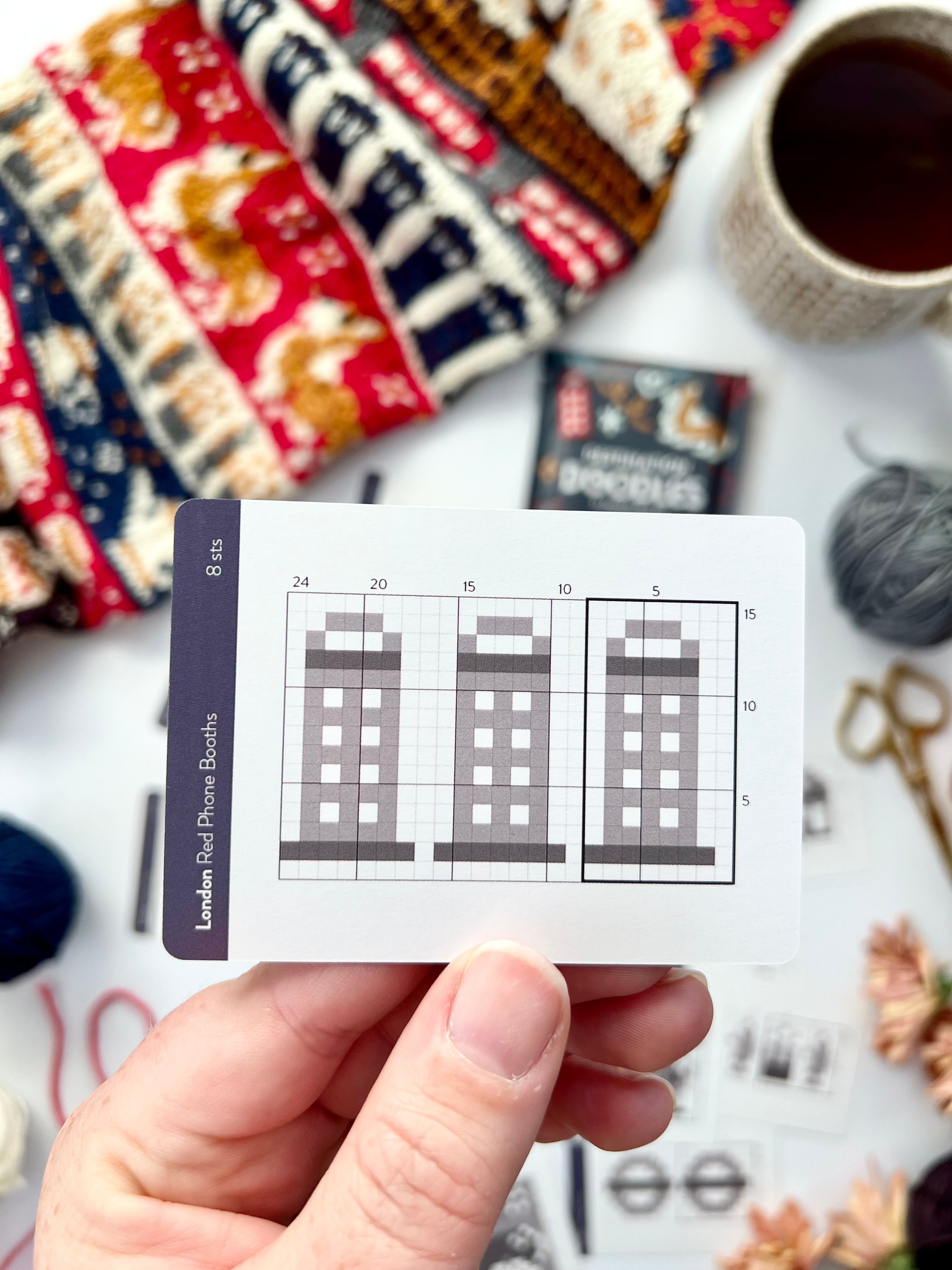Hand holding a London Doodle red phone booths colorwork chart card