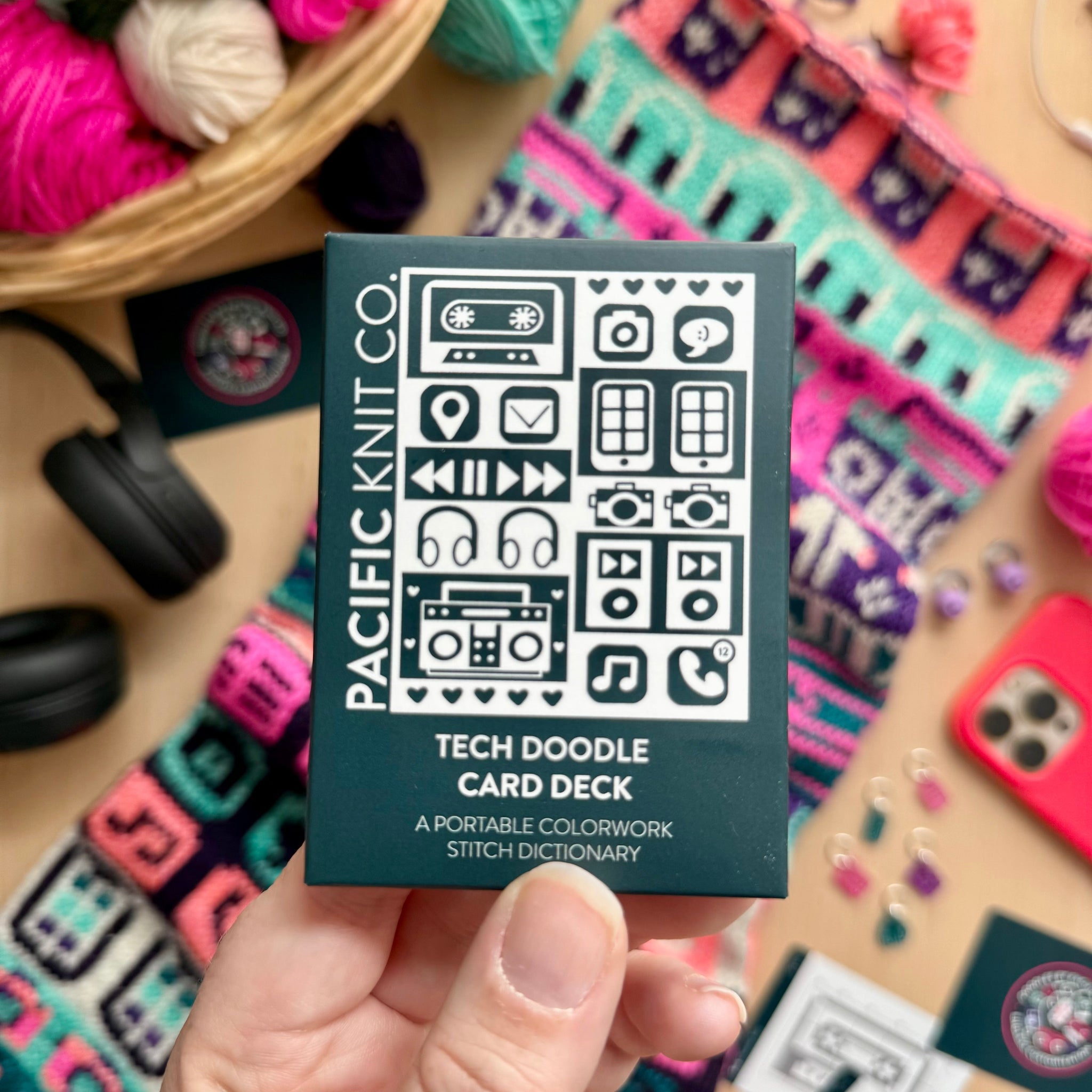 Hand holding the dark teal Tech Doodle Card Deck by Pacific Knit Co tuckbox