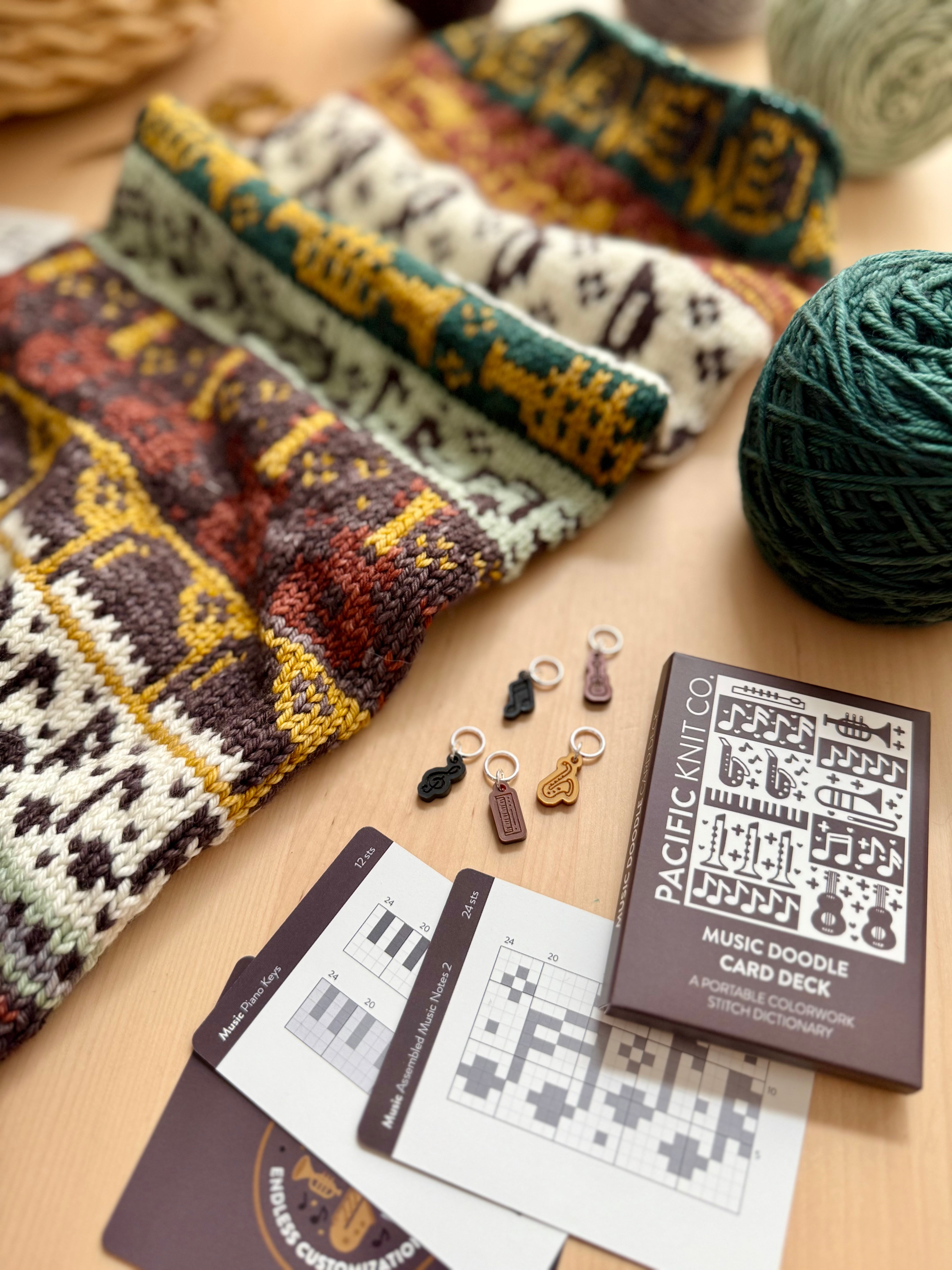 Music Doodle colorwork knits folded beside the deck and chart cards