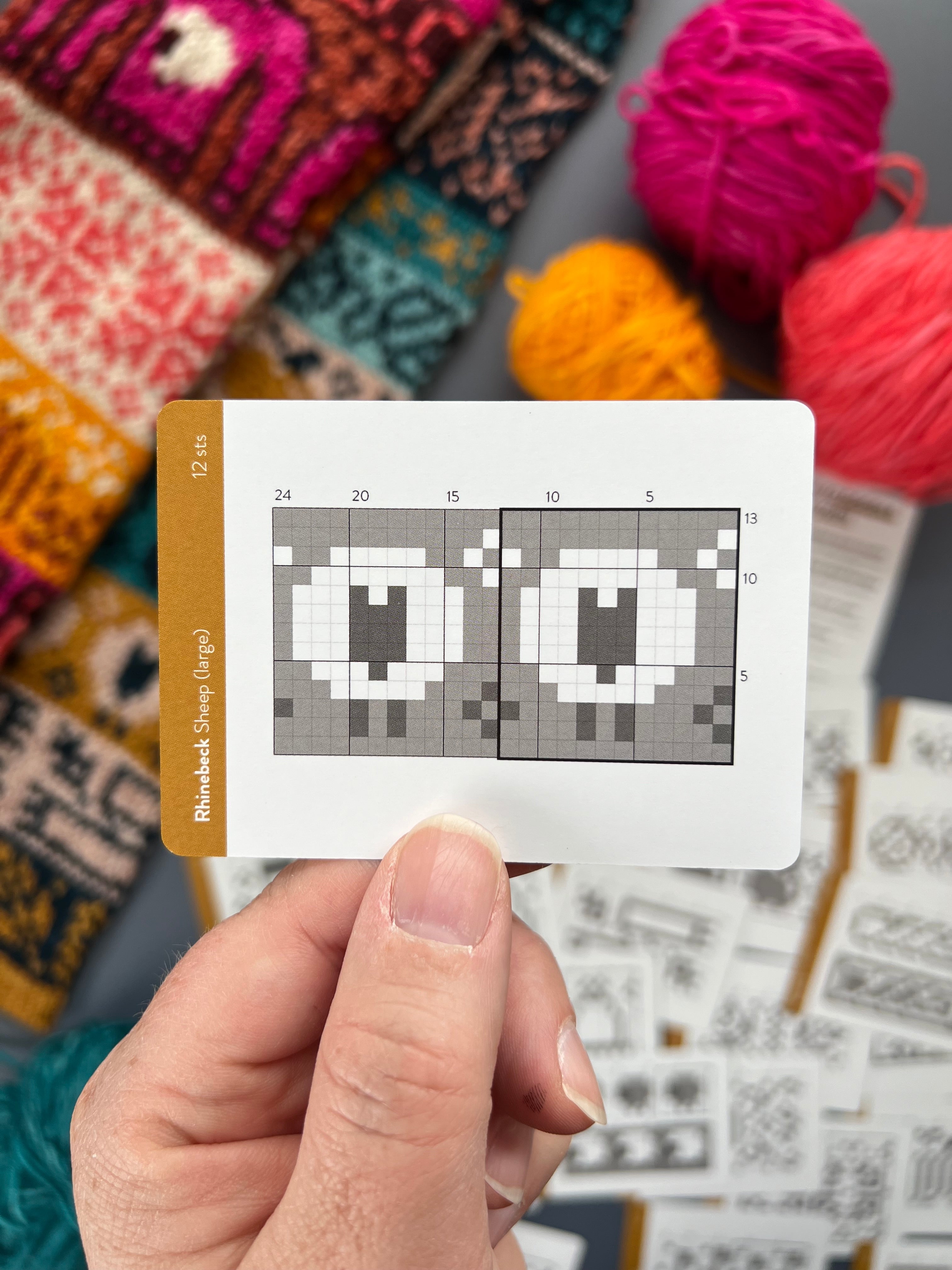 Hand holding a Rhinebeck Doodle sheep colorwork chart card