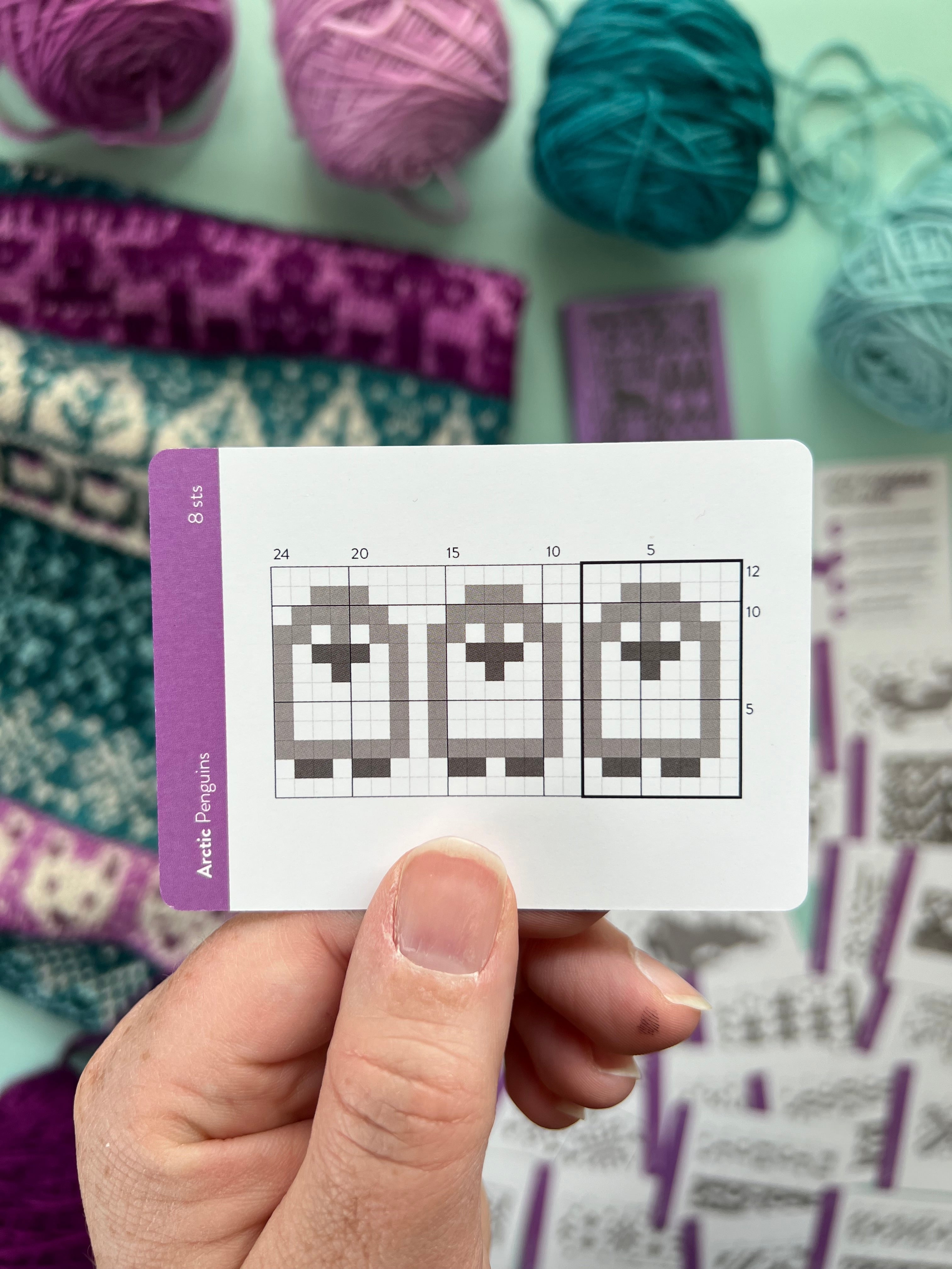 Hand holding an Arctic Doodle penguin colorwork chart card
