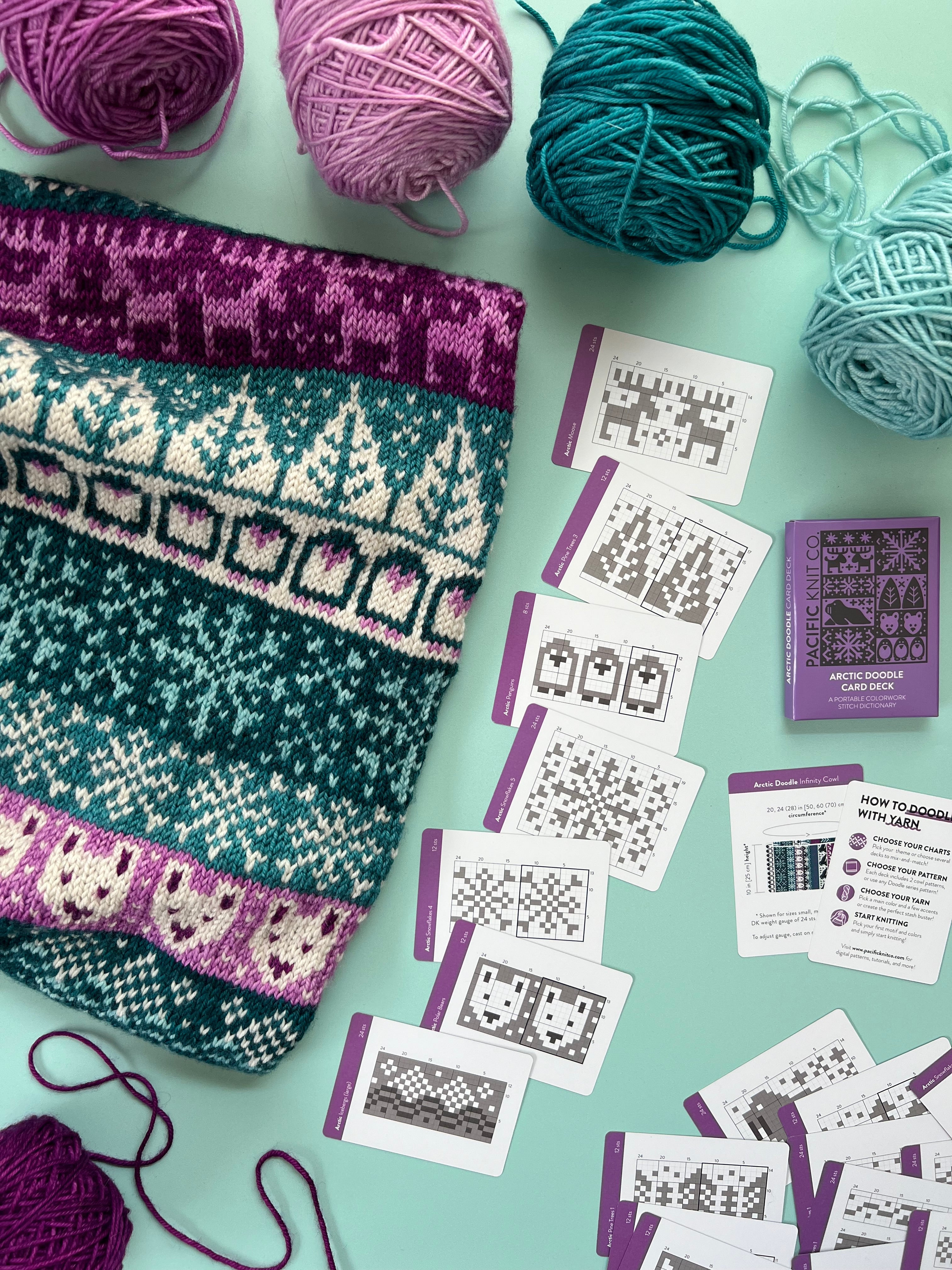 Arctic Doodle colorwork knit with snowy trees beside the deck and chart cards