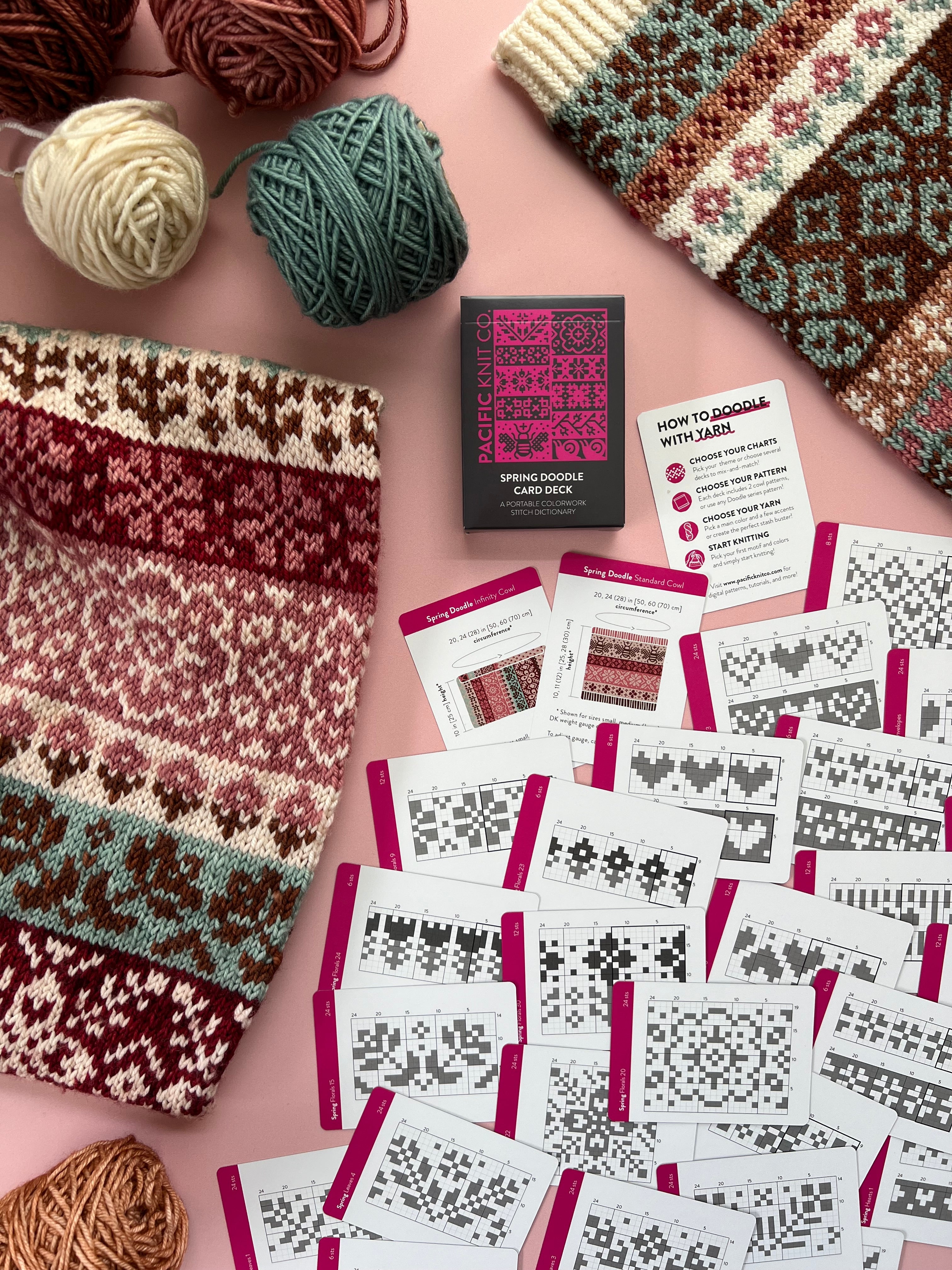 Spring Doodle chart cards laid out beside floral colorwork knits on a pink background