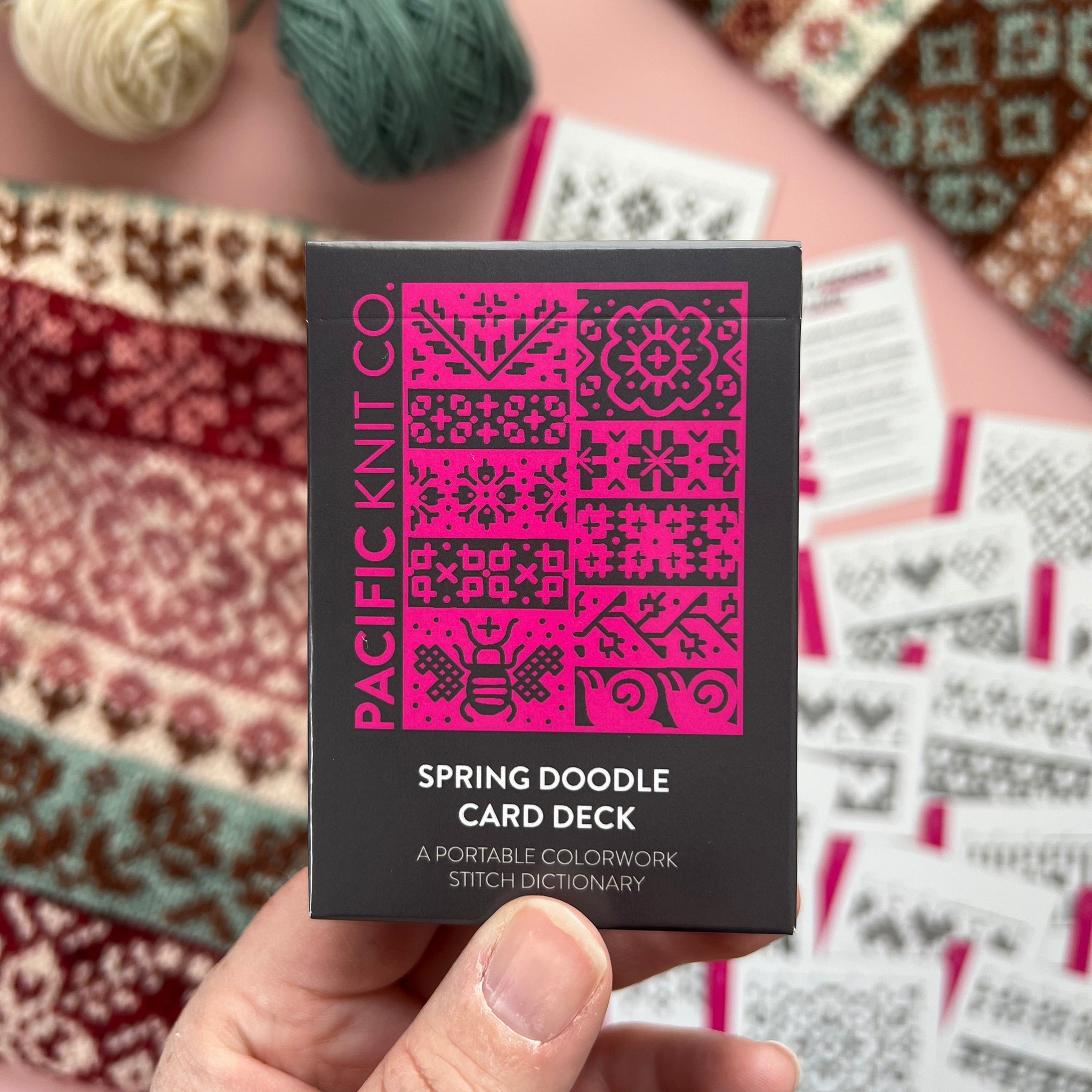 Hand holding the pink and black Spring Doodle Card Deck by Pacific Knit Co tuckbox