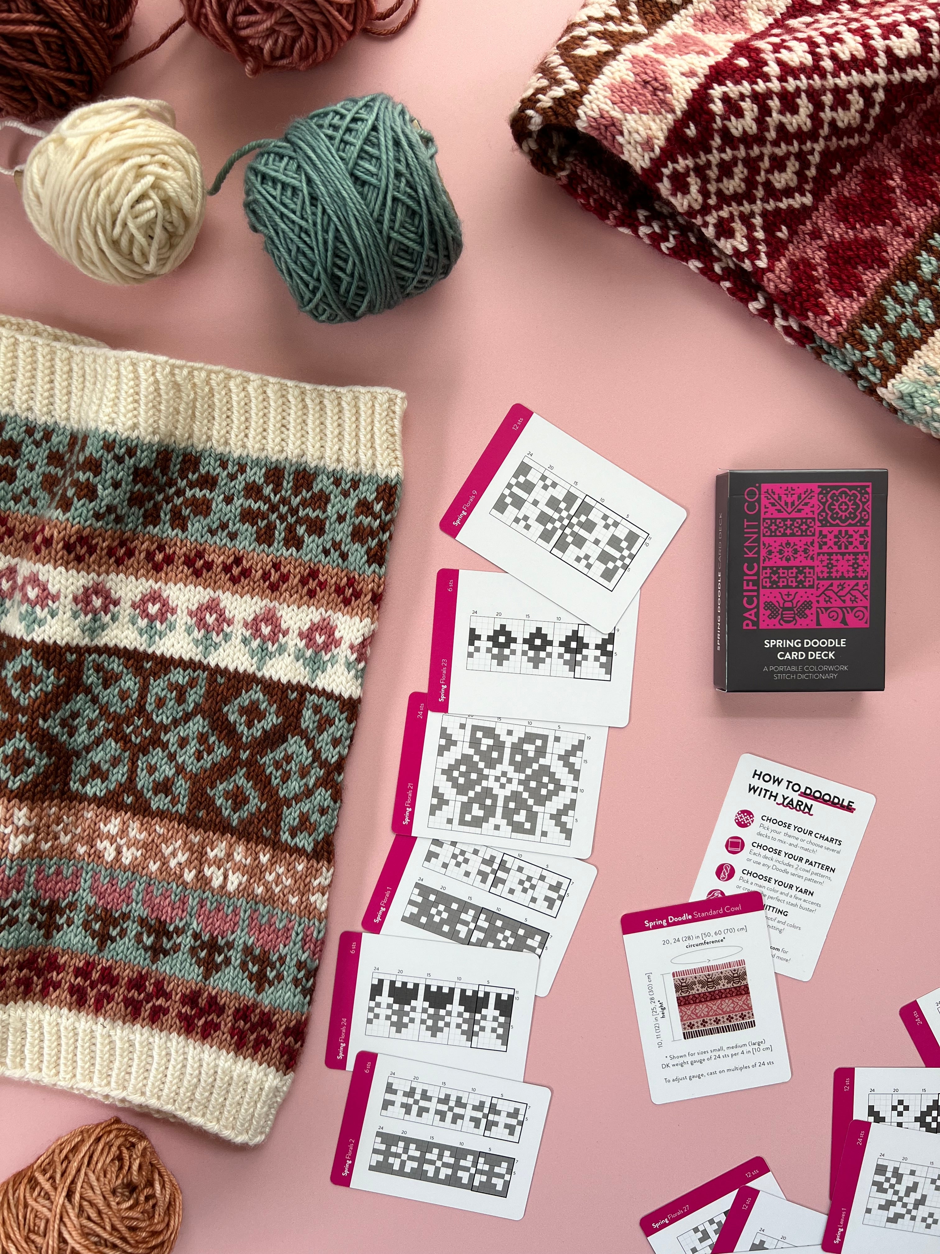 Cream and pink Spring Doodle colorwork cowl with chart cards fanned alongside