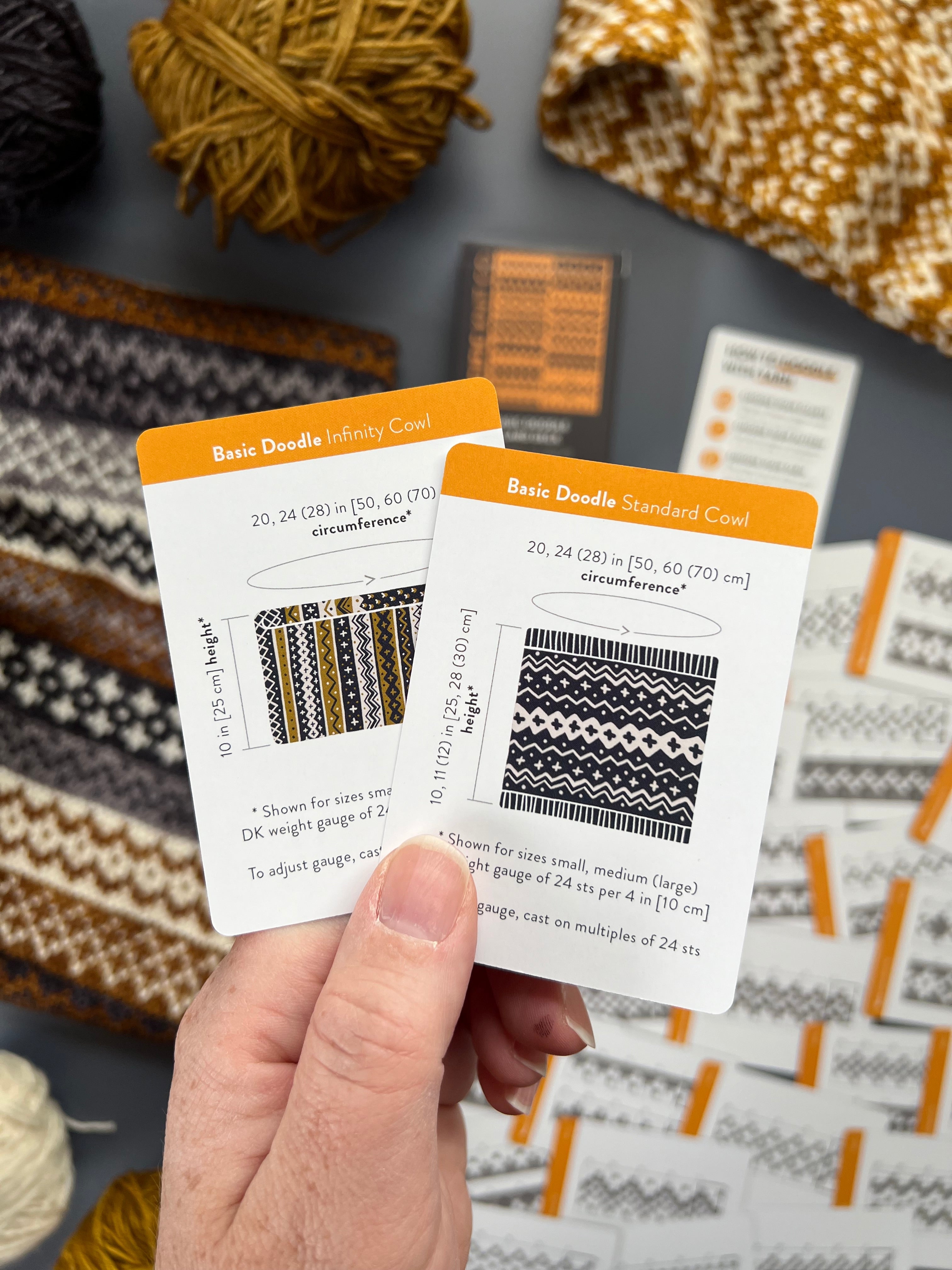 Hand holding the Basic Doodle Infinity Cowl and Standard Cowl schematic cards