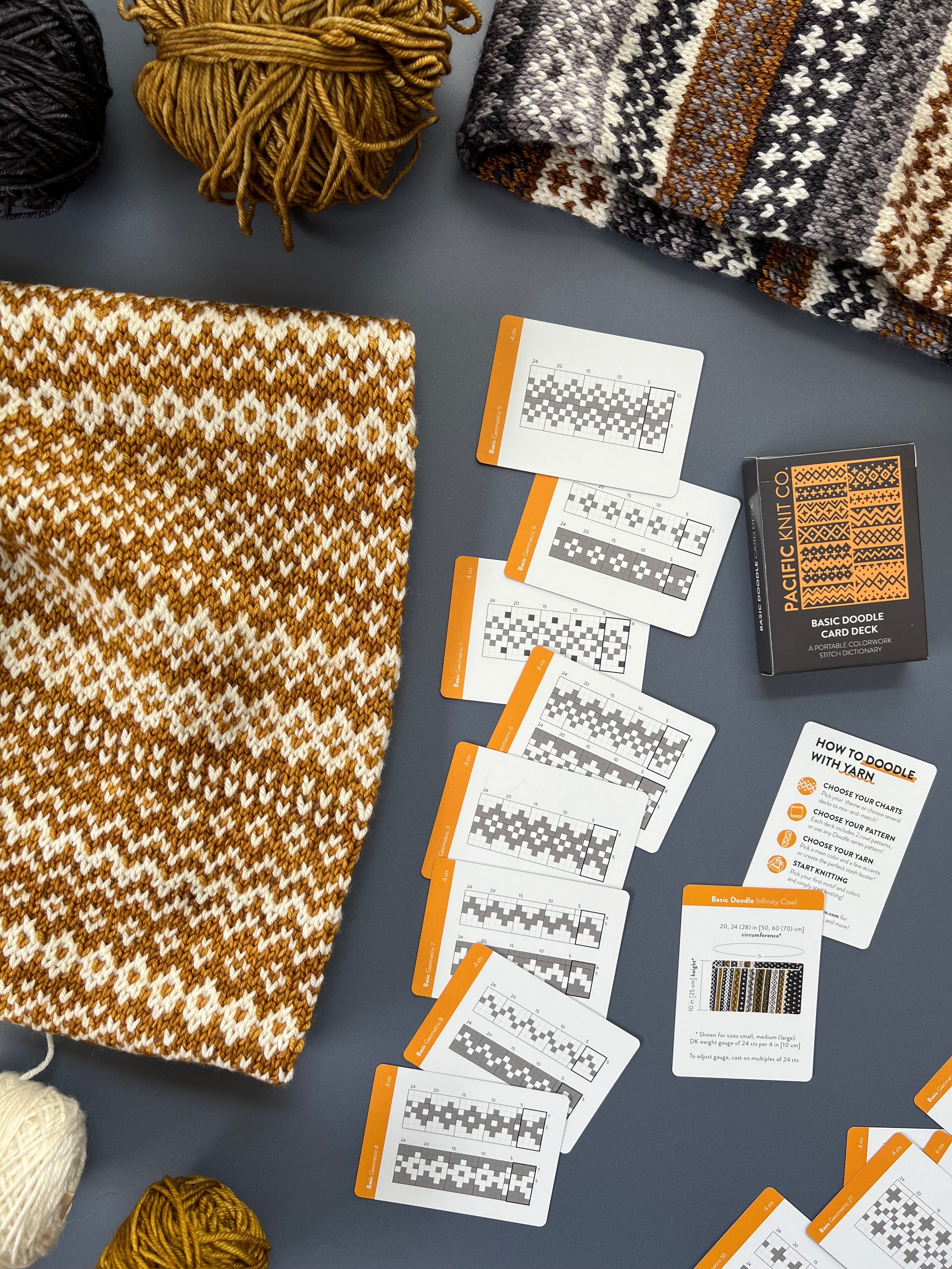 Gold and cream Basic Doodle colorwork cowl with the deck and chart cards on a grey background