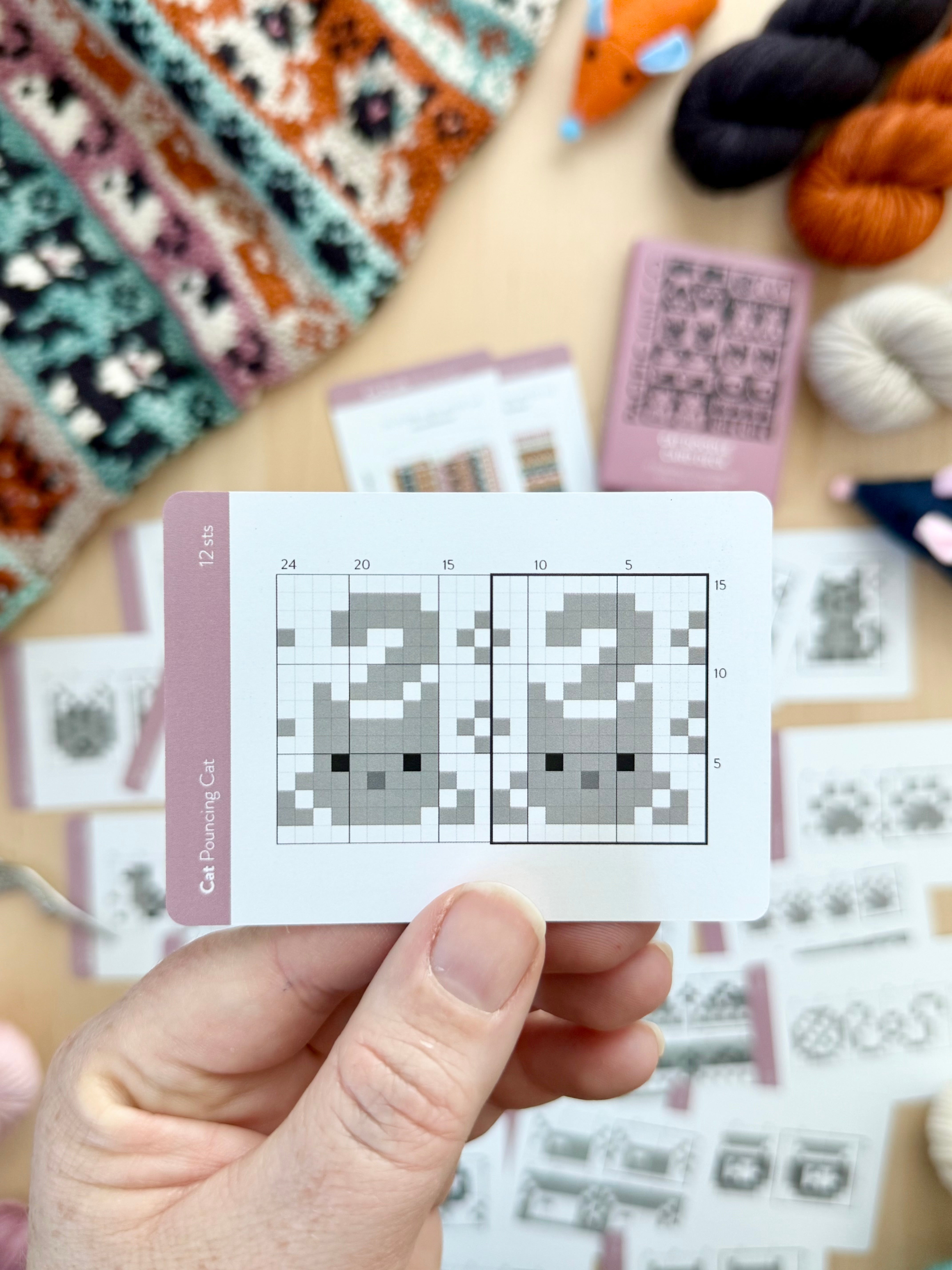 Hand holding a Cat Doodle pouncing cat colorwork chart card