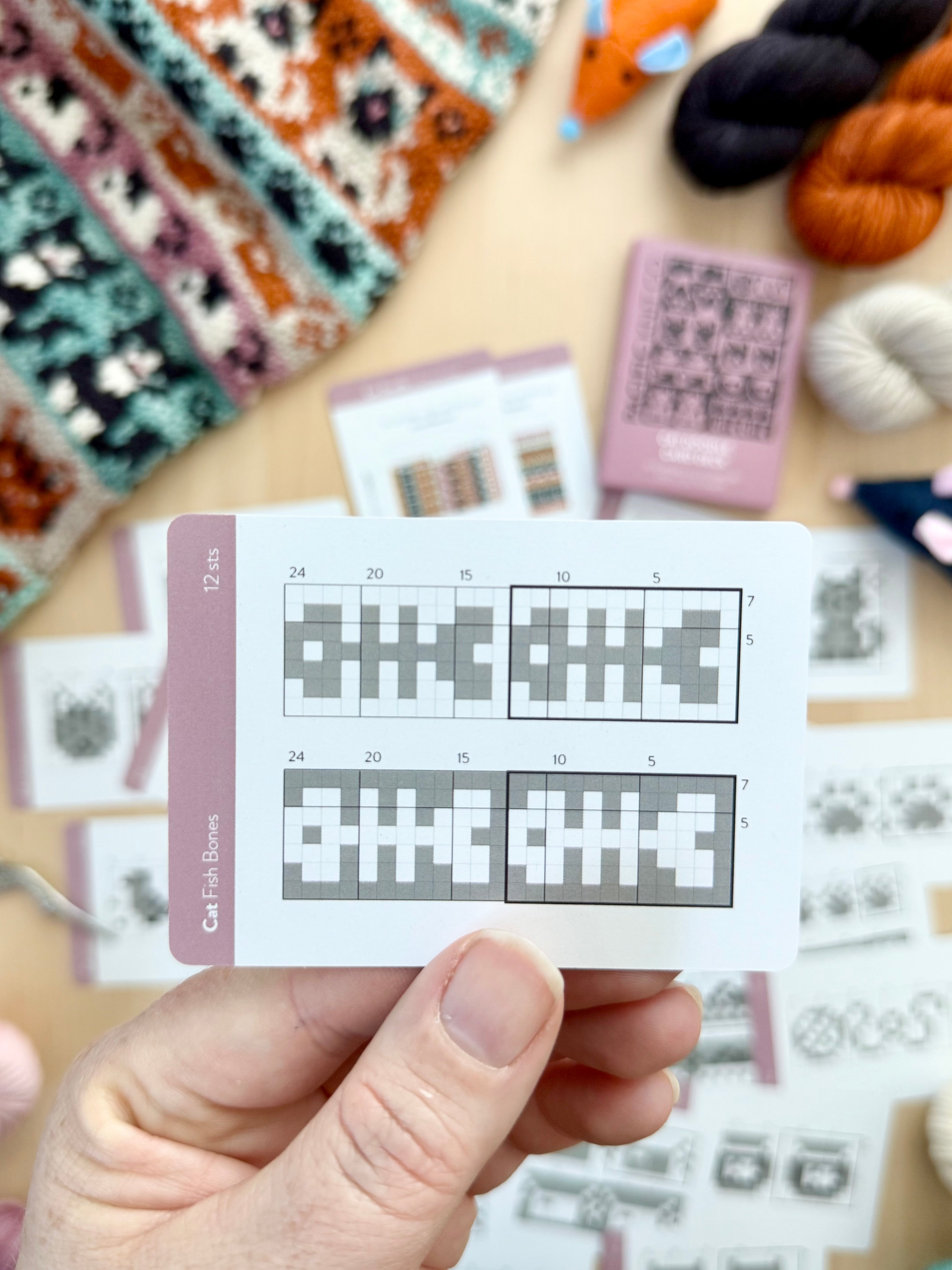 Hand holding a Cat Doodle fish bones colorwork chart card