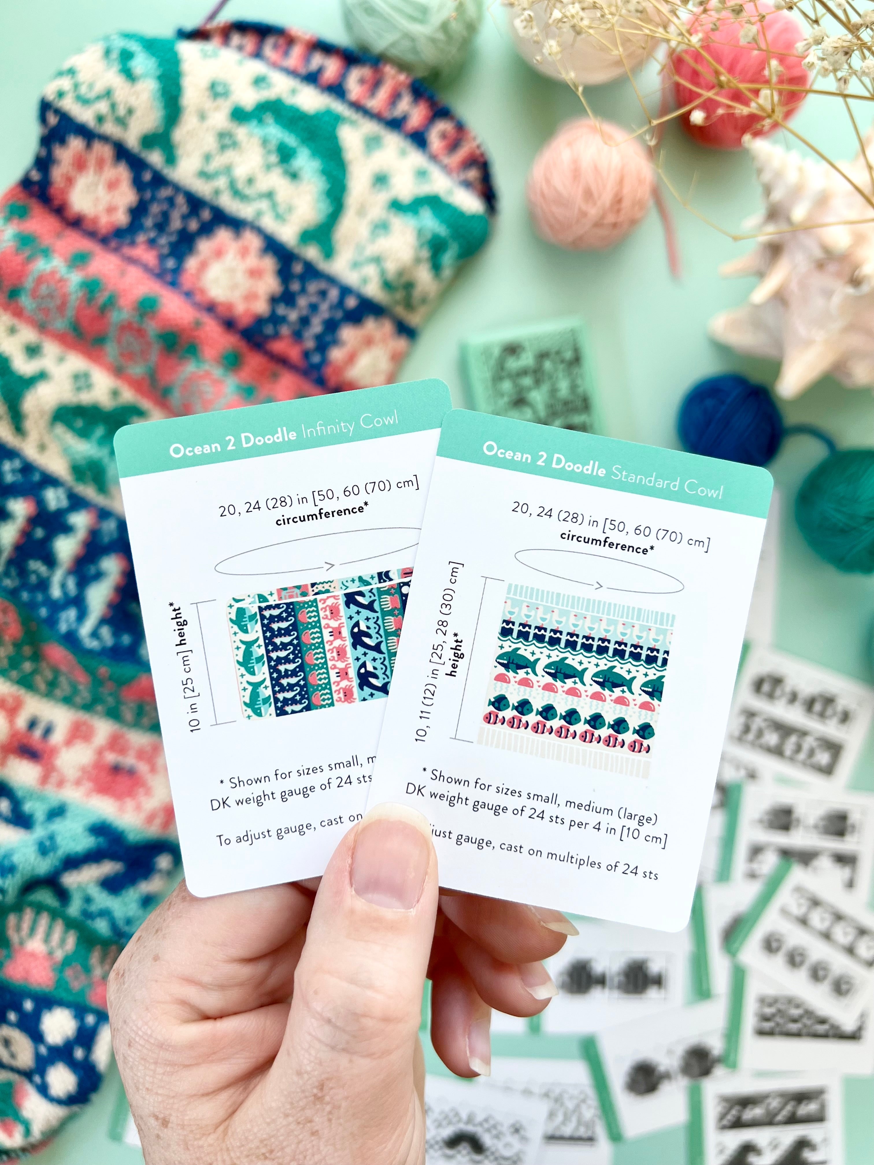 Hand holding the Ocean 2 Doodle Infinity Cowl and Standard Cowl schematic cards