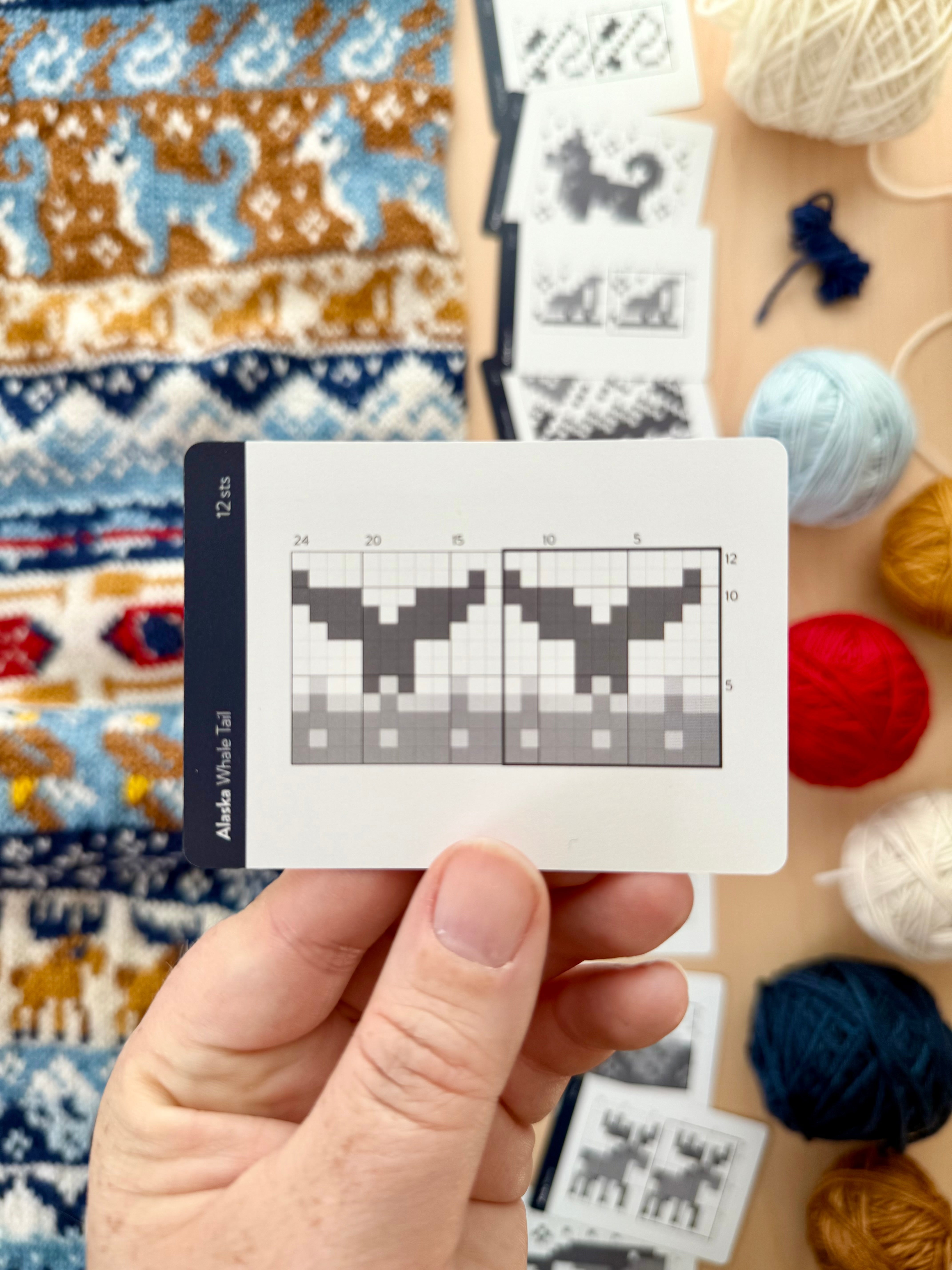 Hand holding an Alaska Doodle whale tail colorwork chart card