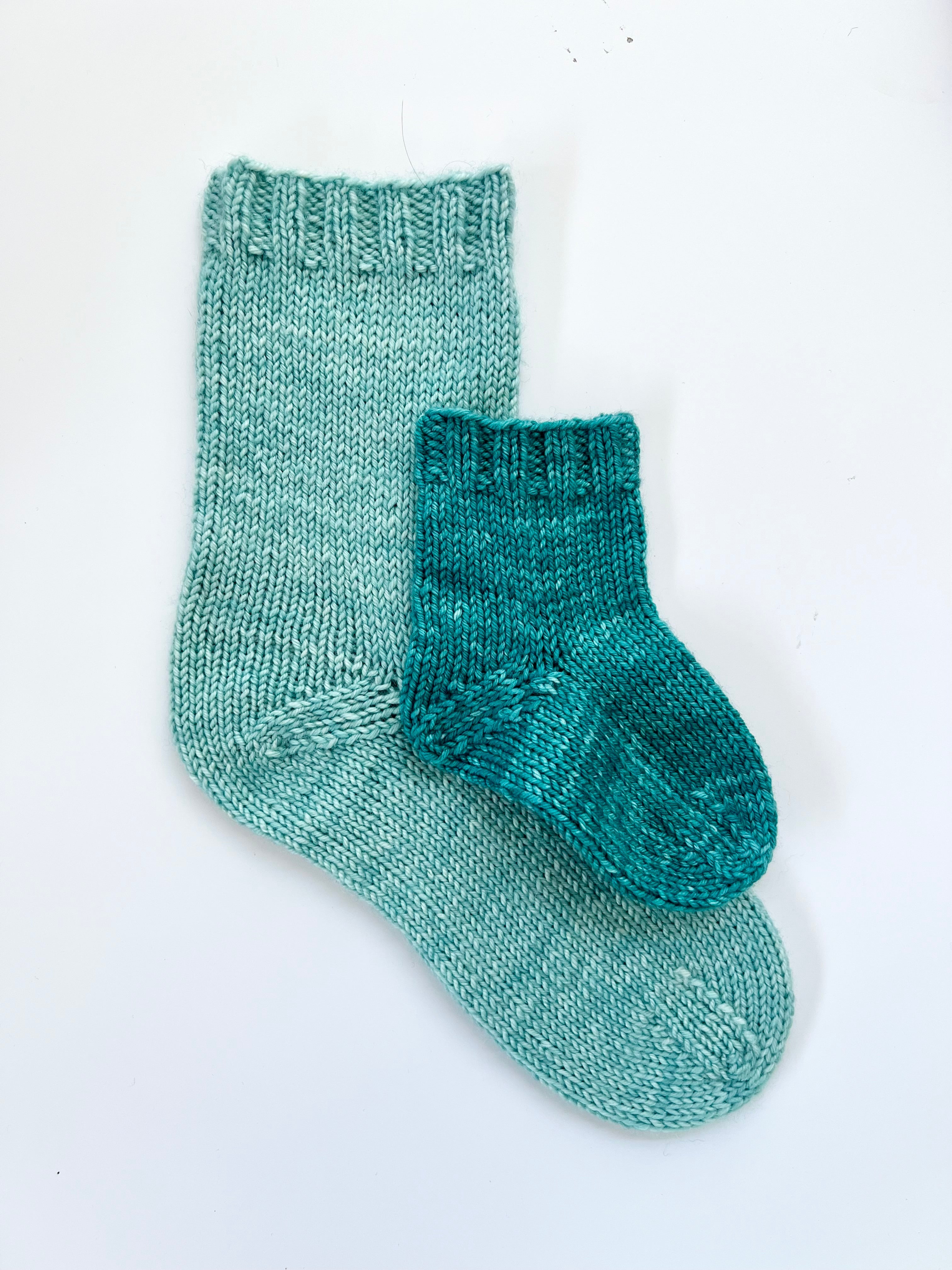 Two Base Doodle Top-Down Socks in light and dark teal on a white background