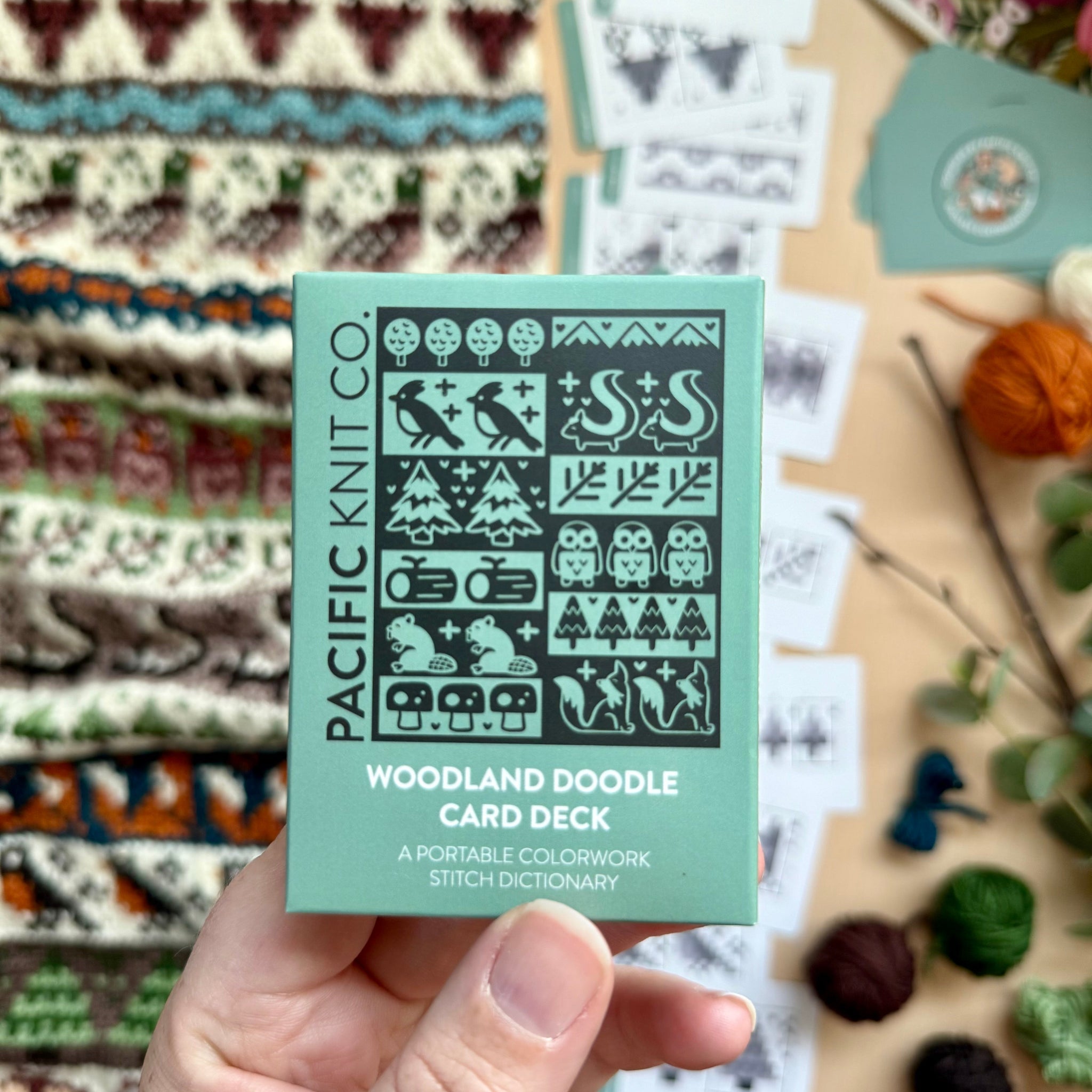 Hand holding the green Woodland Doodle Card Deck by Pacific Knit Co tuckbox