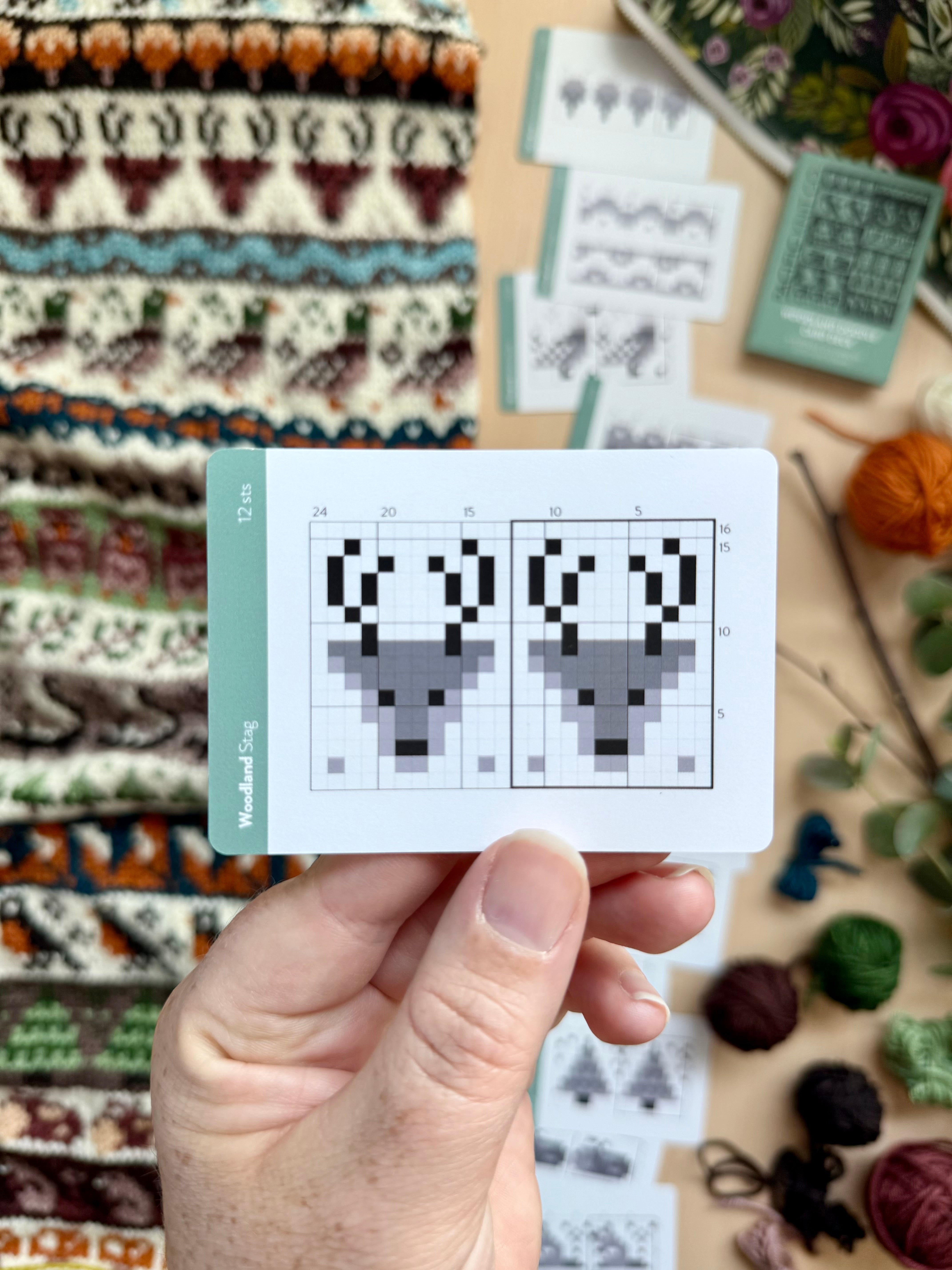 Hand holding a Woodland Doodle stag colorwork chart card