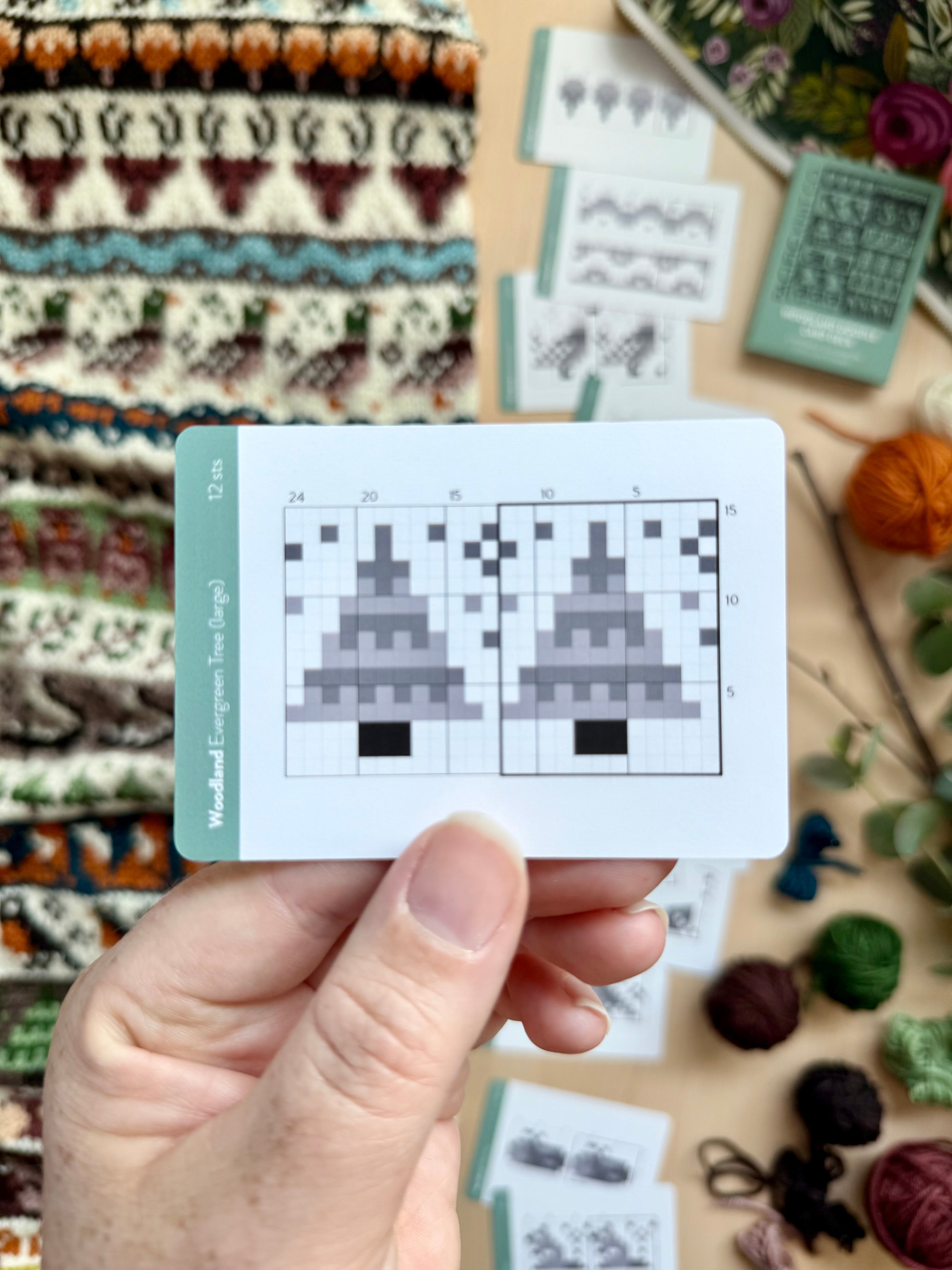 Hand holding a Woodland Doodle evergreen tree colorwork chart card