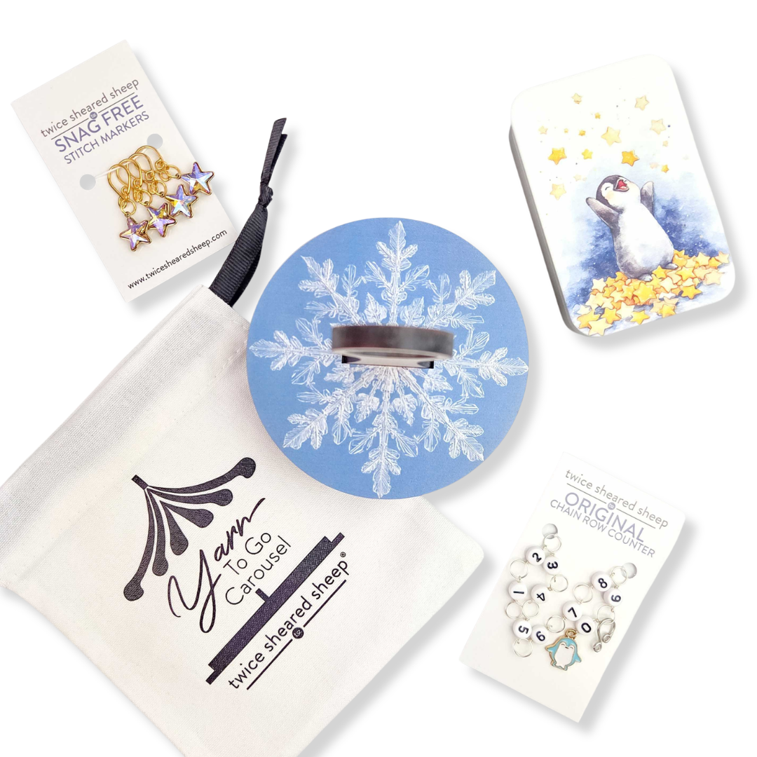 2026 LYS Exclusive Winter Gift Box flat lay showing all contents including snowflake pin, yarn, stitch markers, branded cards, and star confetti on white background