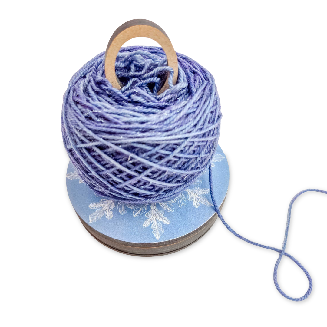2026 LYS Exclusive Winter Gift Box styled display showing periwinkle blue yarn, snowflake ornament, and branded accessories arranged together